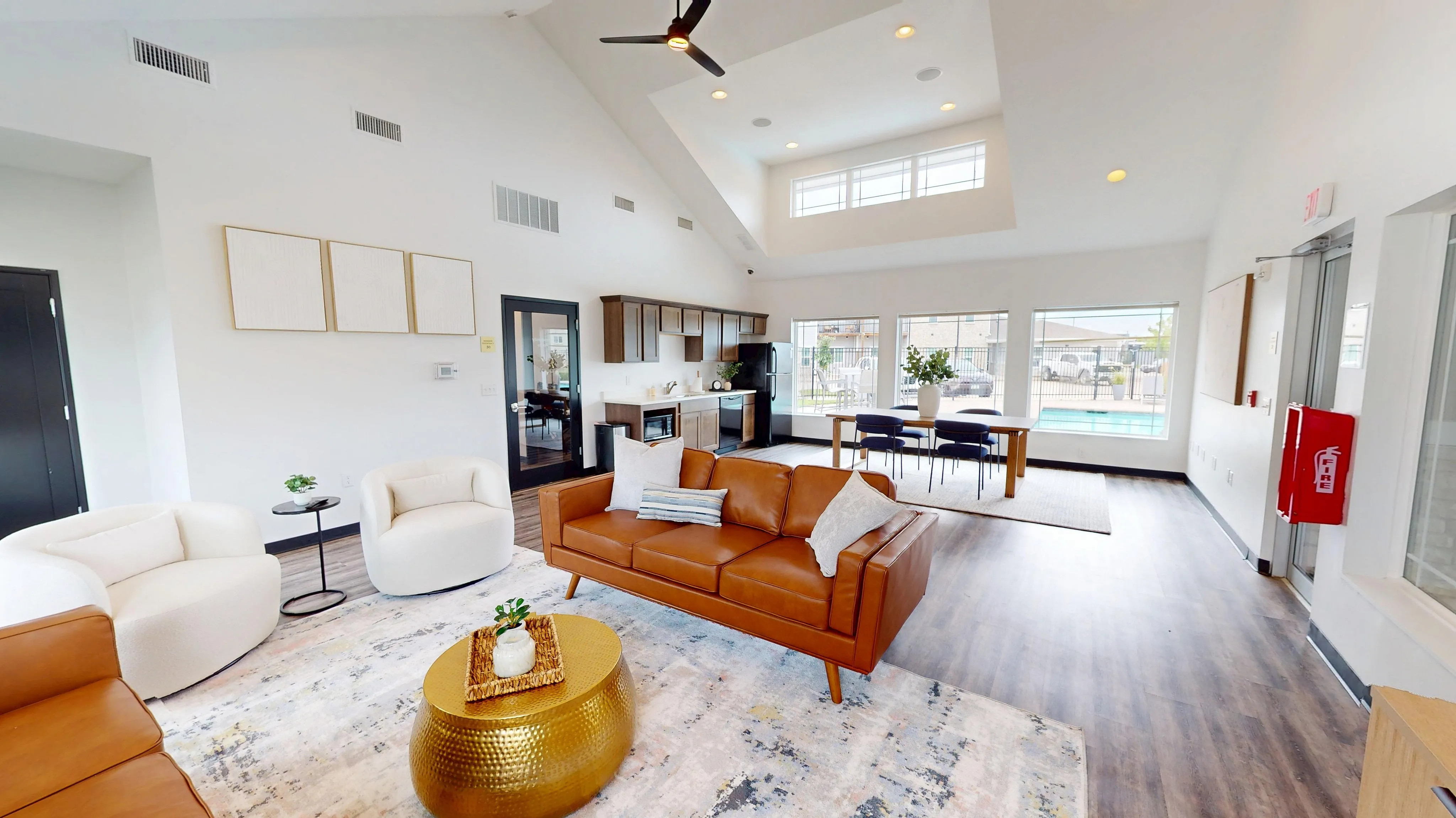 Chic open-concept living space featuring contemporary furniture, a cozy seating area, modern kitchen amenities, and large windows overlooking a pool.