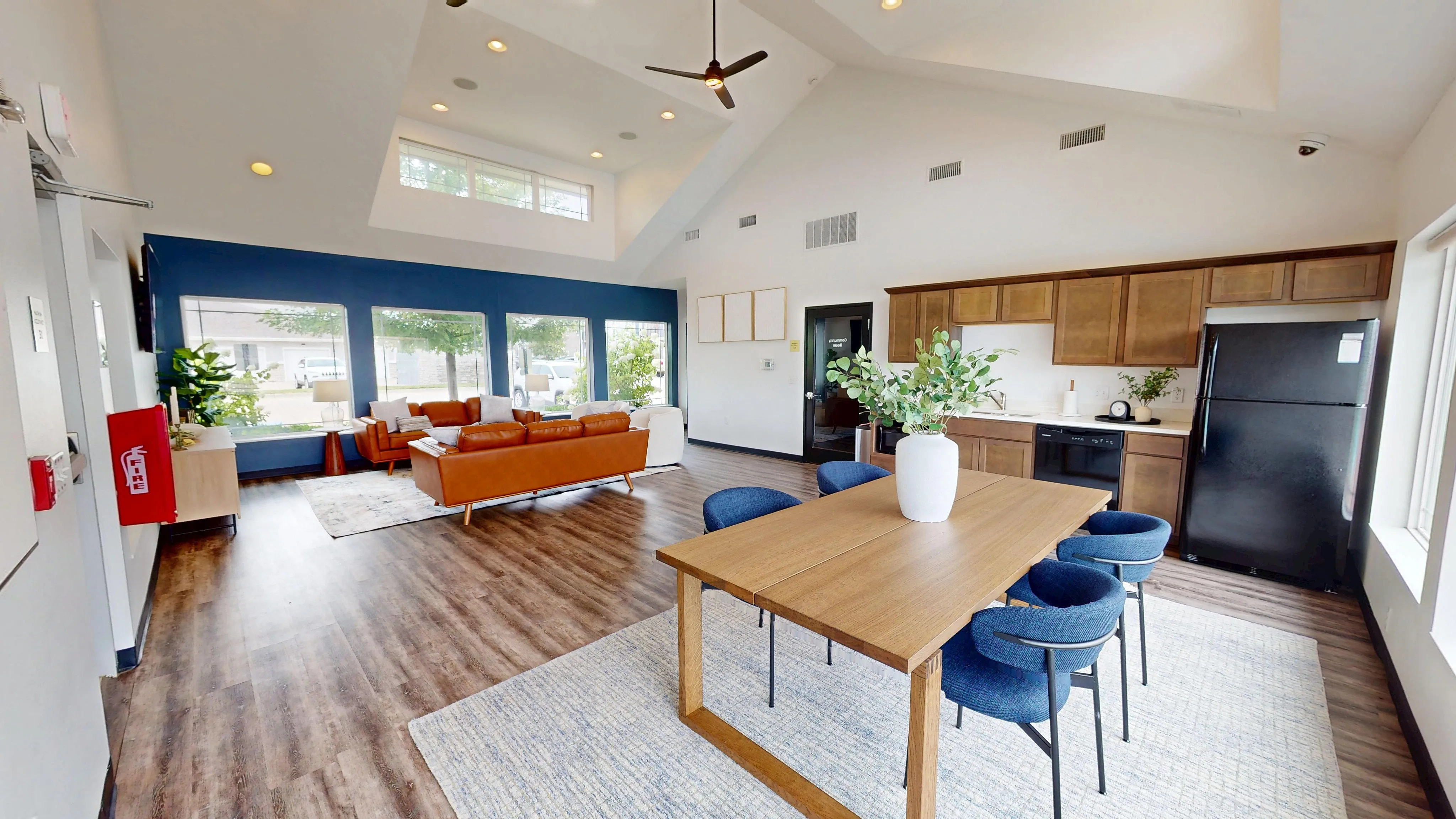 Charming modern living space with vaulted ceilings, featuring an open kitchen, stylish dining area, and cozy seating with large windows providing abundant natural light.