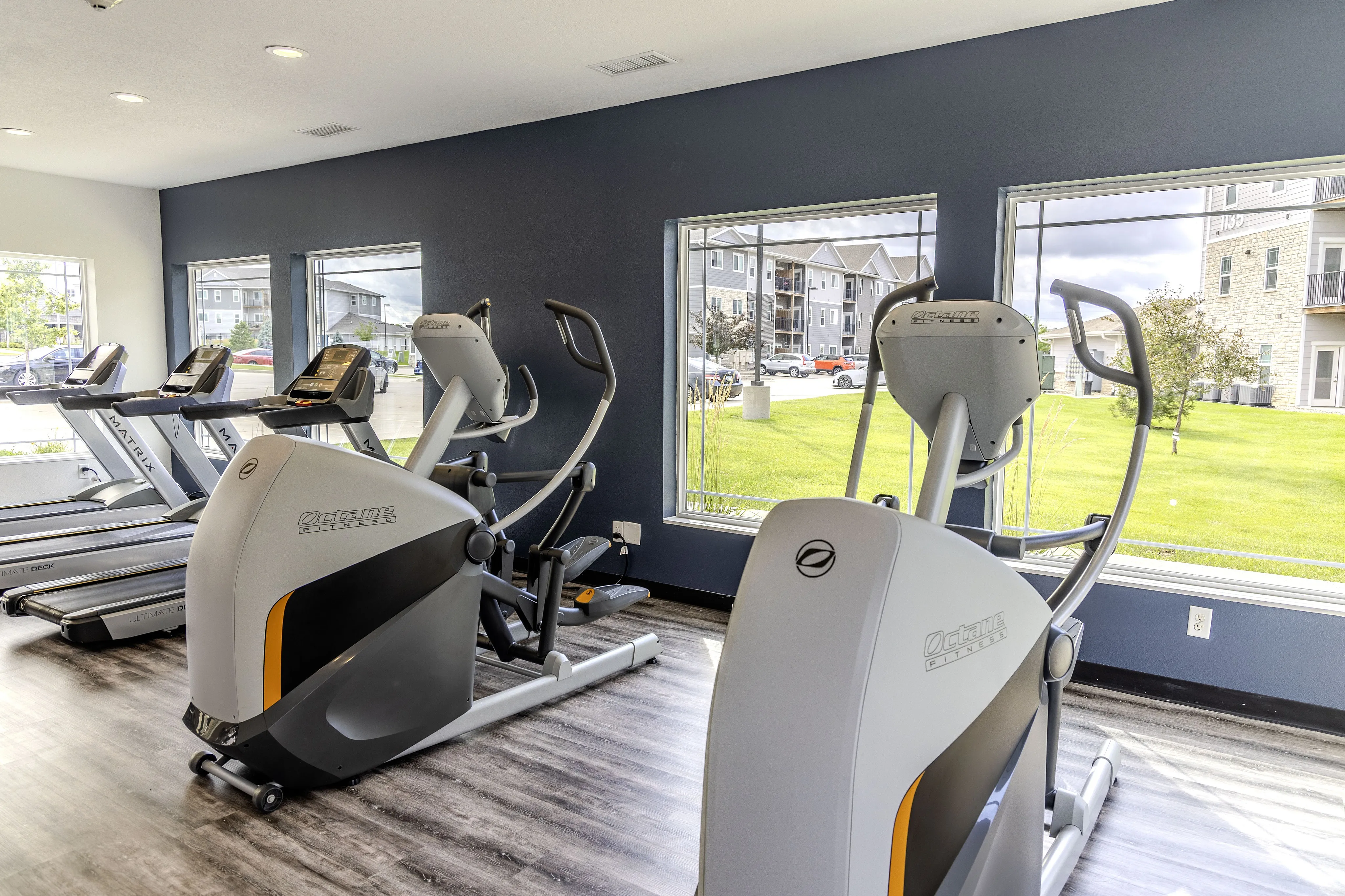 Modern apartment gym with state-of-the-art equipment and bright, scenic views of the lush outdoor landscape.