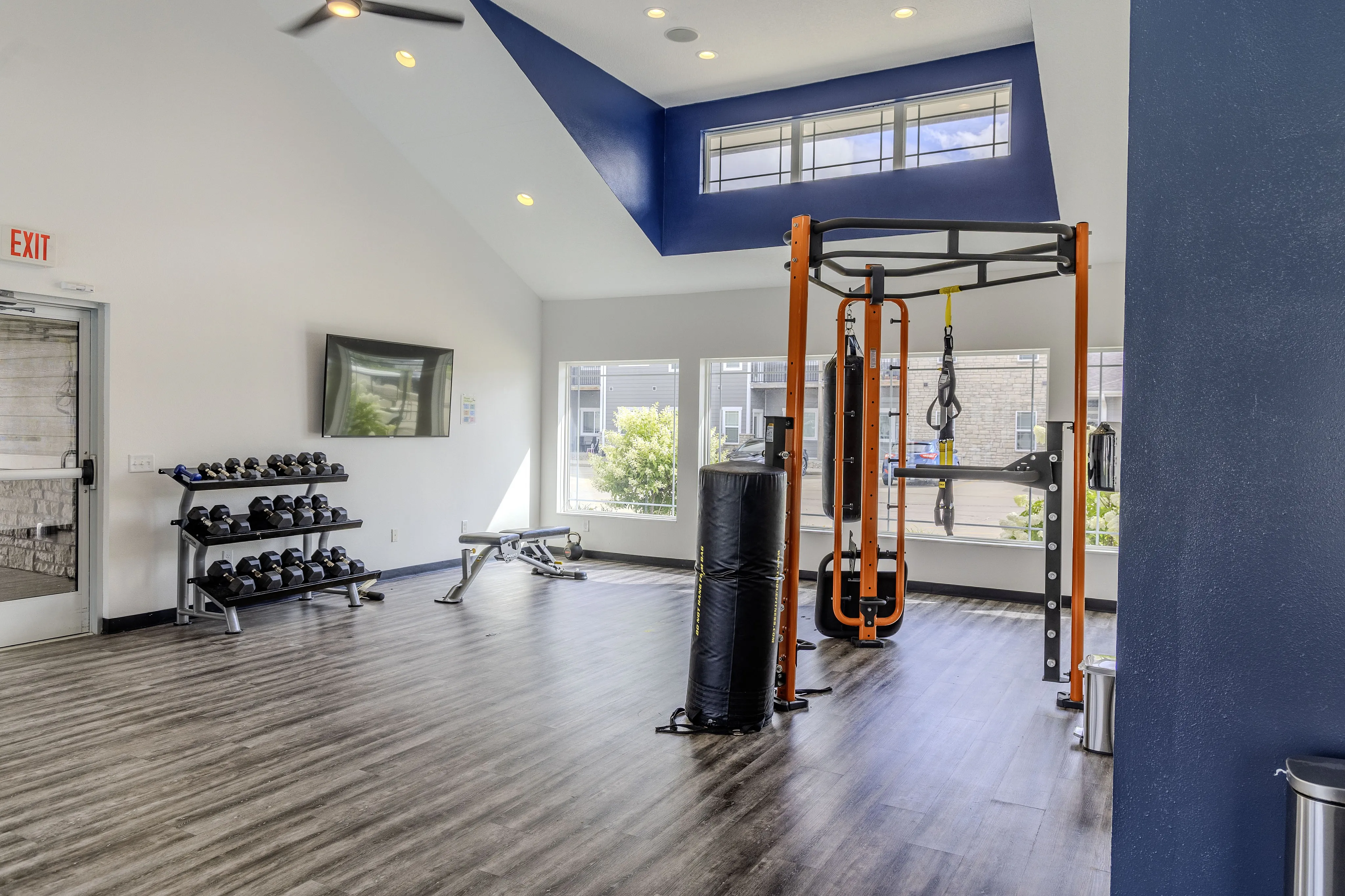 Modern fitness center with high ceilings, vibrant blue accents, state-of-the-art gym equipment, and ample natural light.