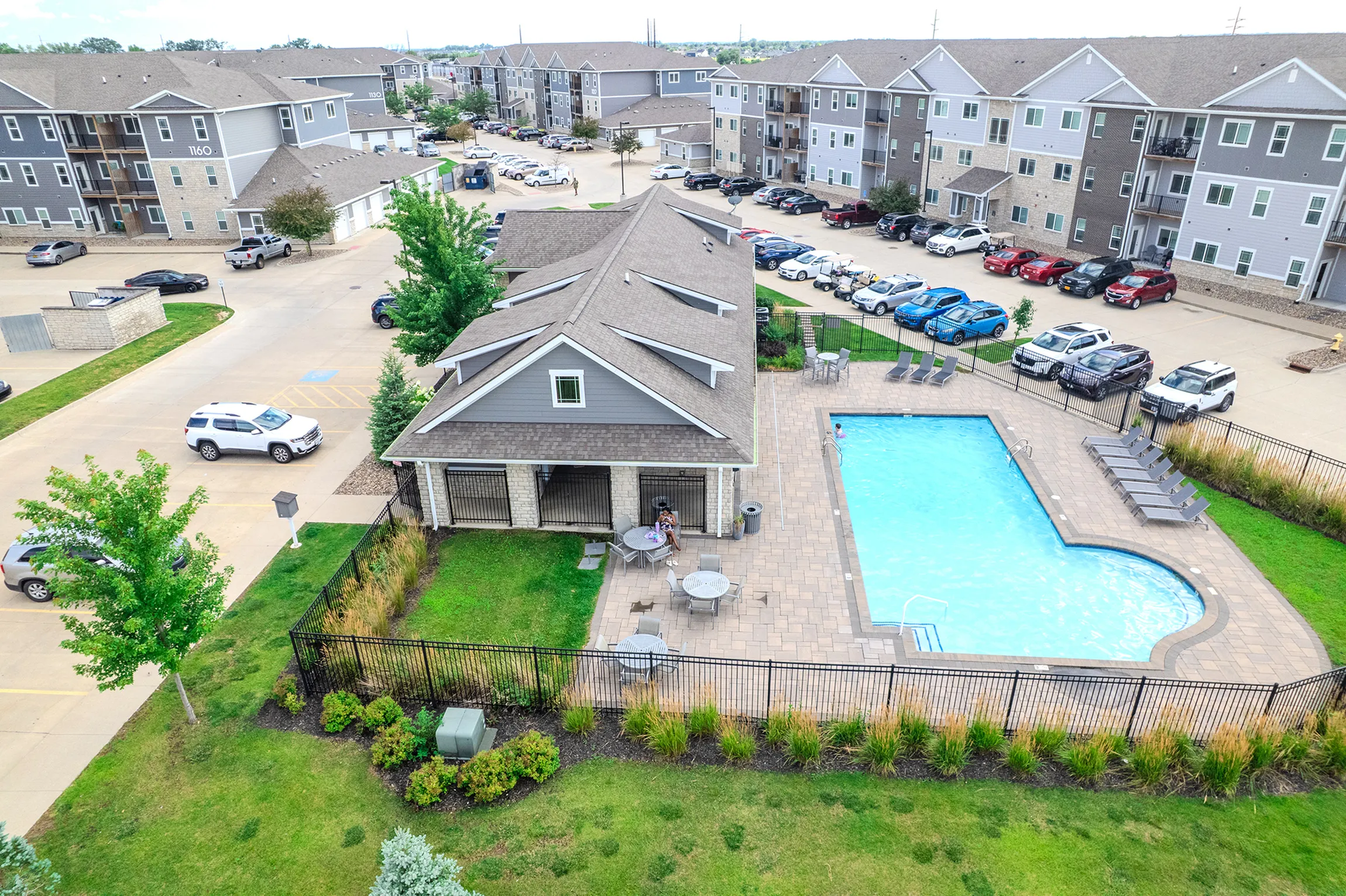 Inviting apartment complex with an outdoor pool, modern architecture, and ample parking, creating a lively community atmosphere.