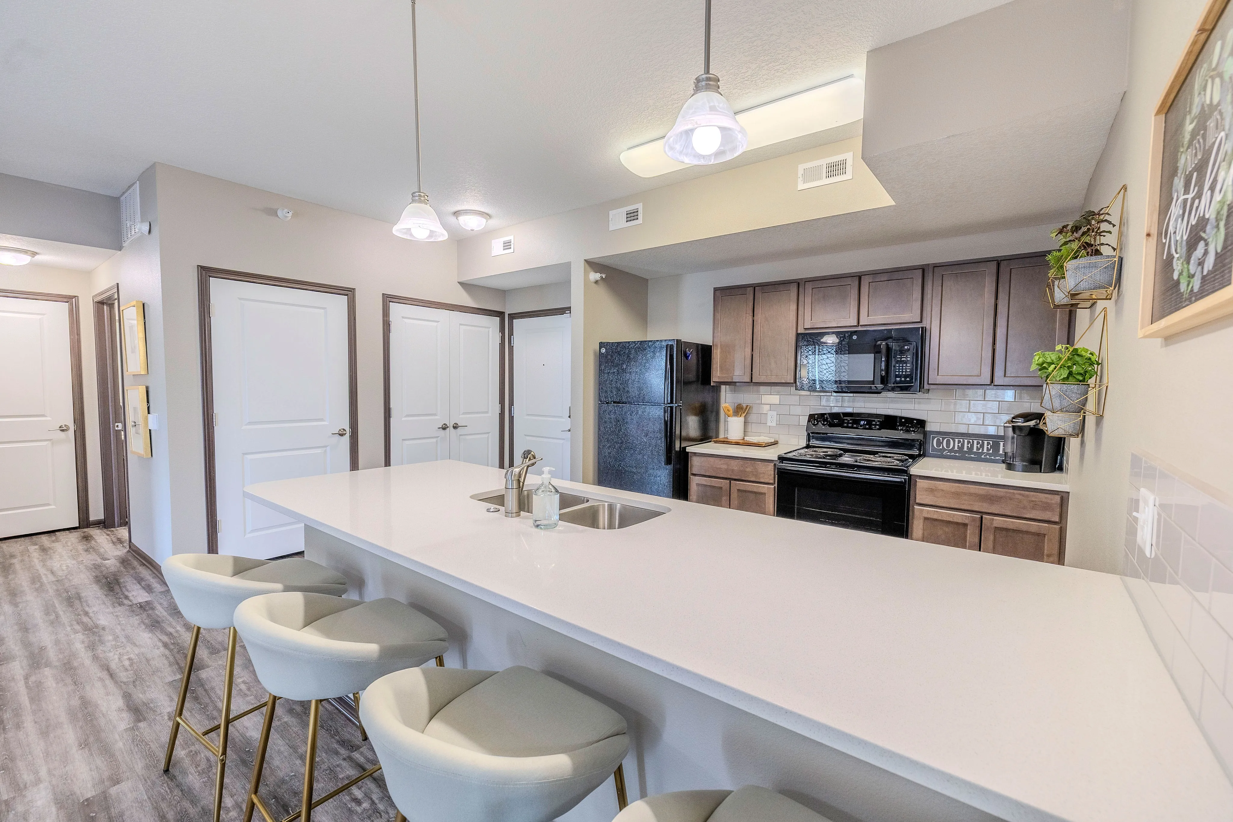 Modern kitchen with sleek countertops, cozy bar stools, and stylish pendant lighting, offering a welcoming space for gatherings.
