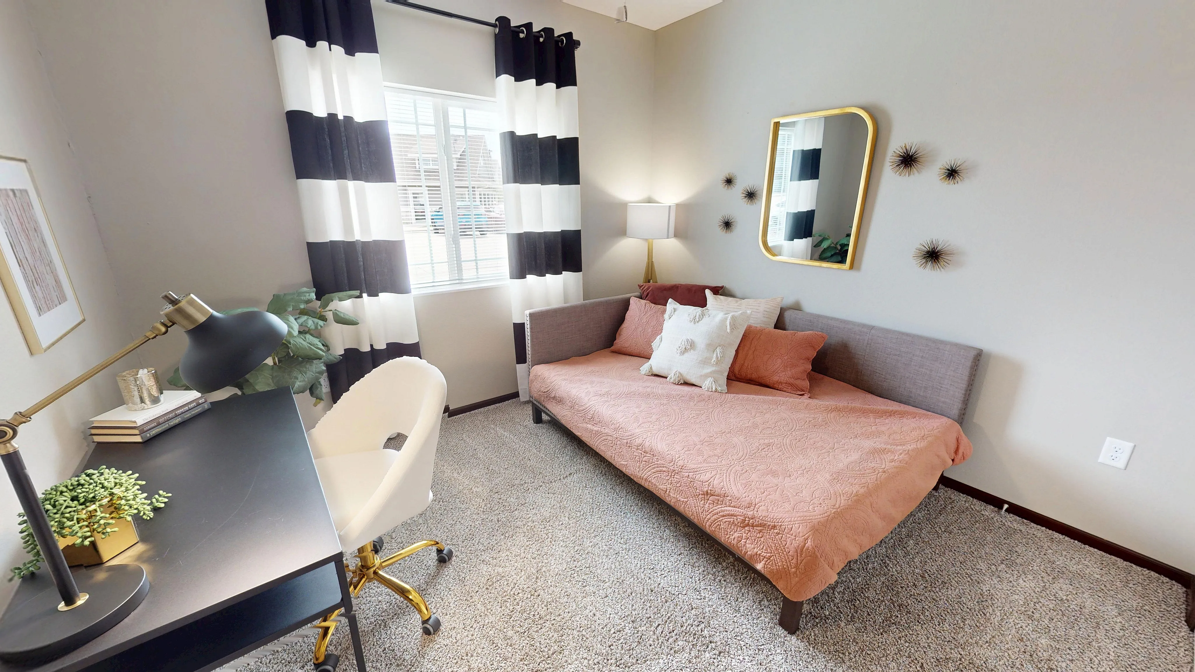 Inviting bedroom with chic decor, featuring a stylish daybed with accent pillows, modern desk, and elegant black and white curtains.