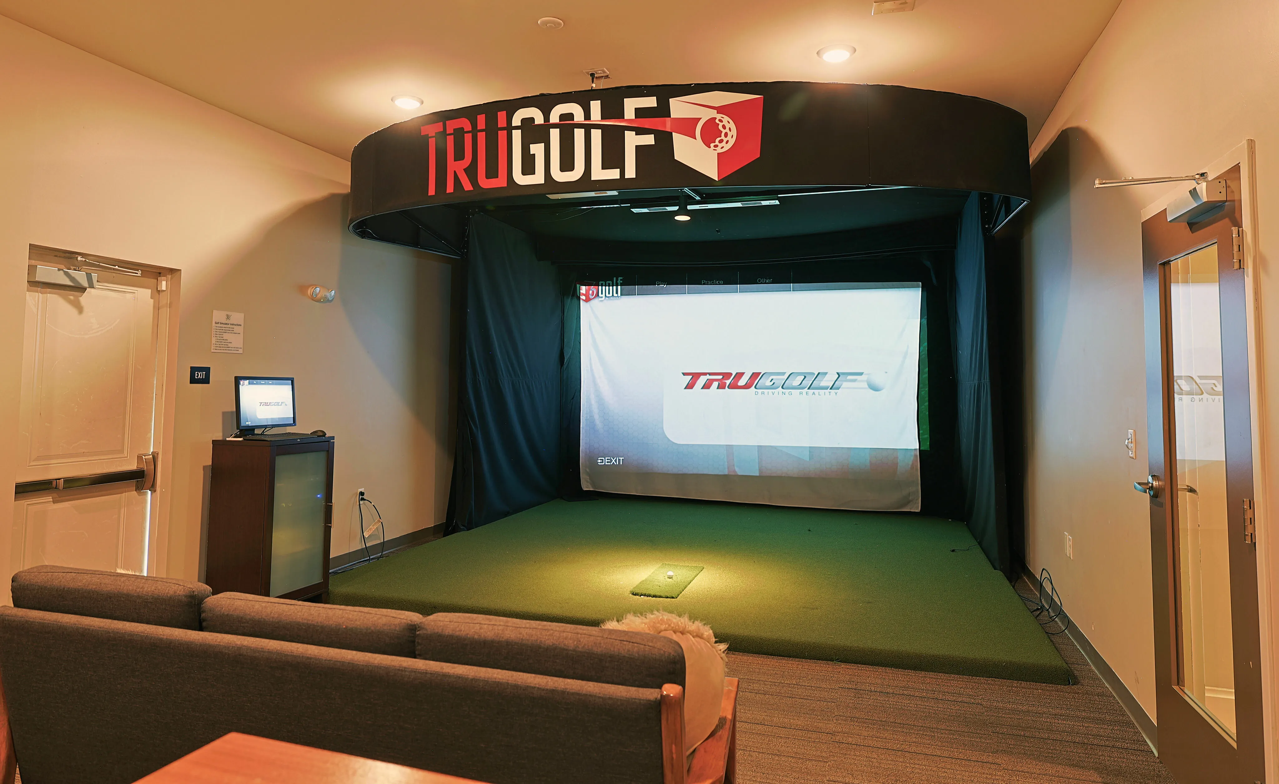 Luxurious indoor golf simulator setup with cozy seating, featuring TruGolf technology for an immersive golfing experience.