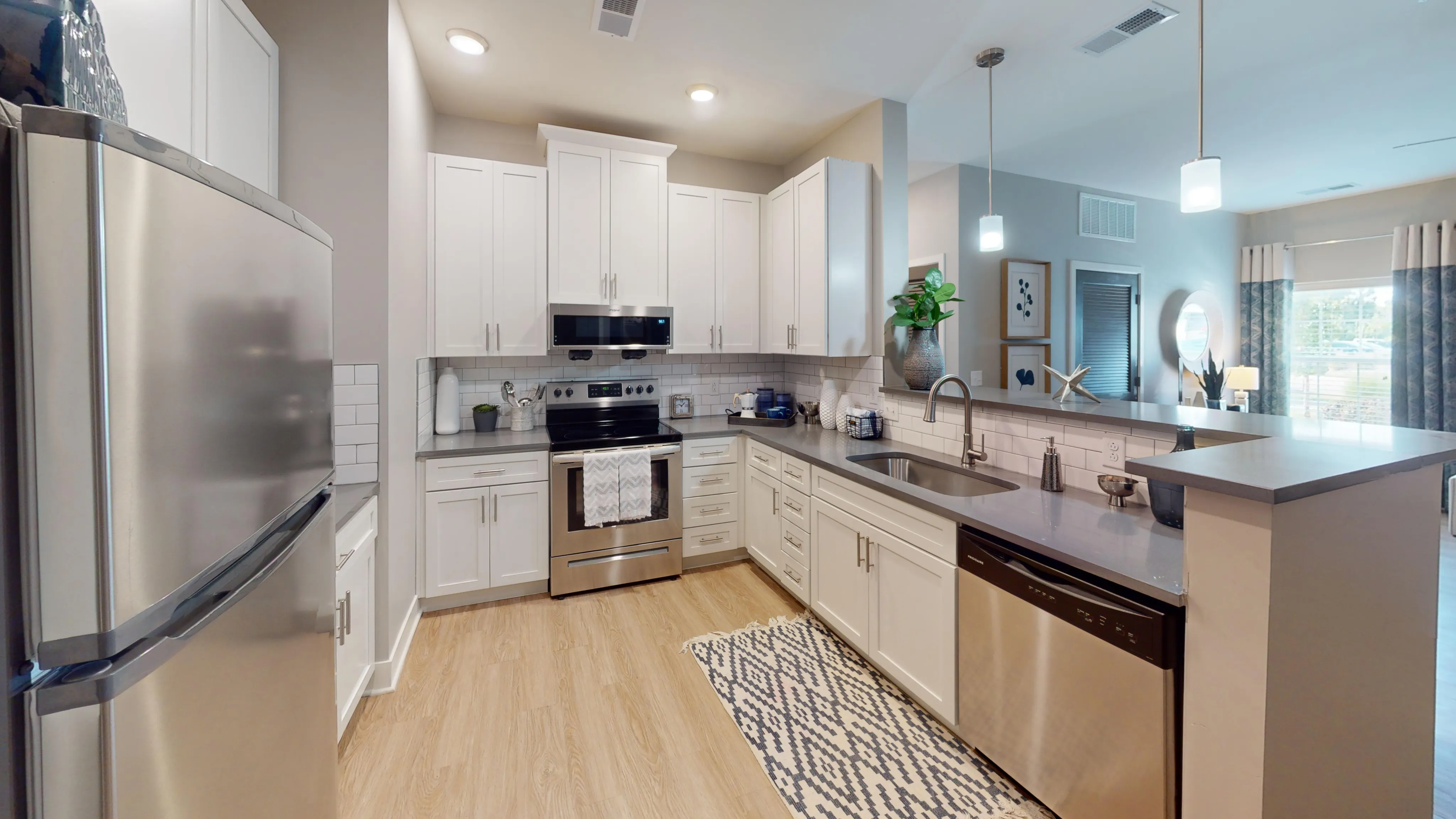 Elegant modern kitchen with sleek stainless steel appliances, white cabinetry, and a stylish breakfast bar featuring pendant lighting and an inviting decor.
