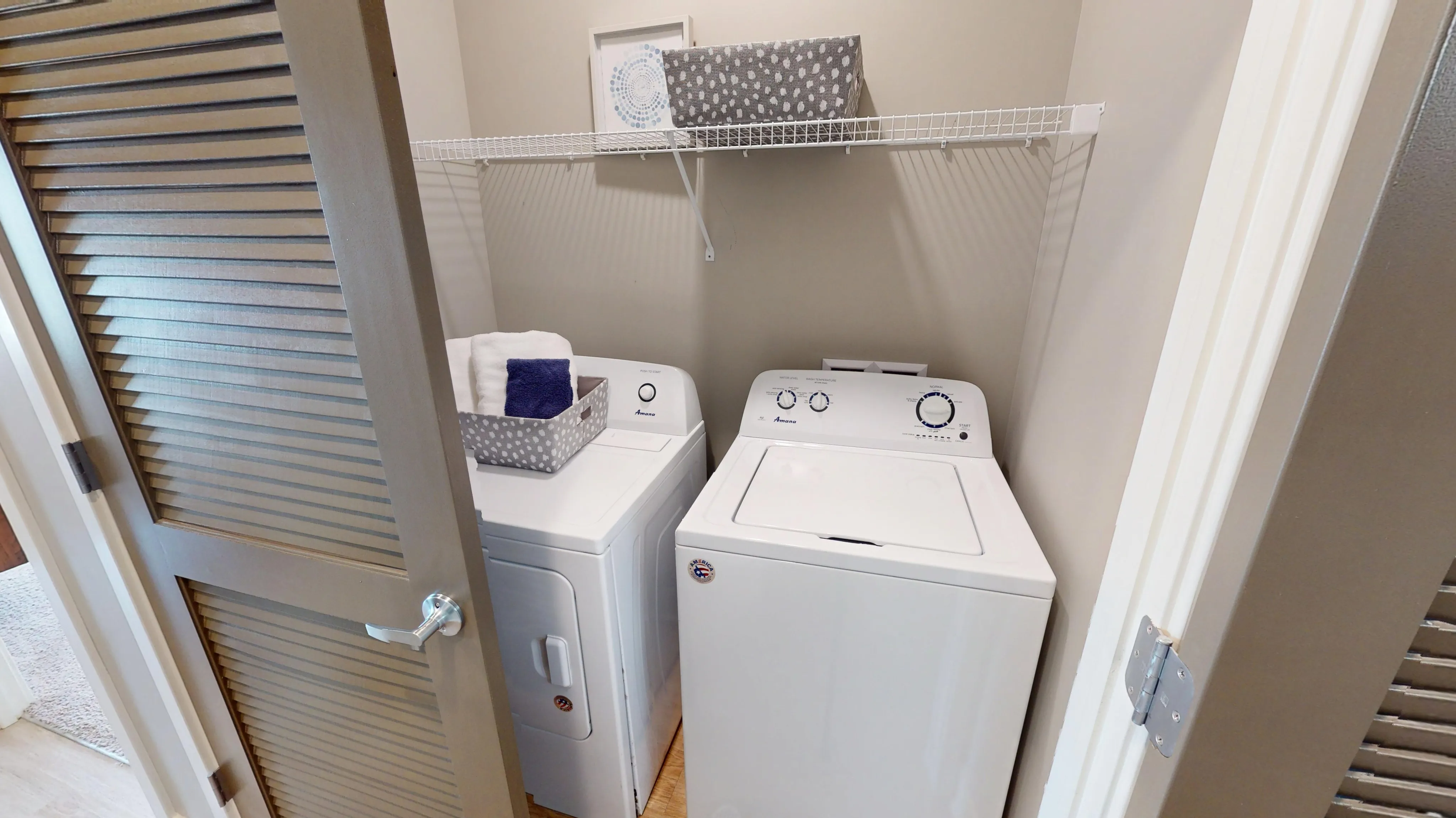 Modern laundry closet featuring sleek washer and dryer with convenient shelving, adding practicality and style to any apartment.