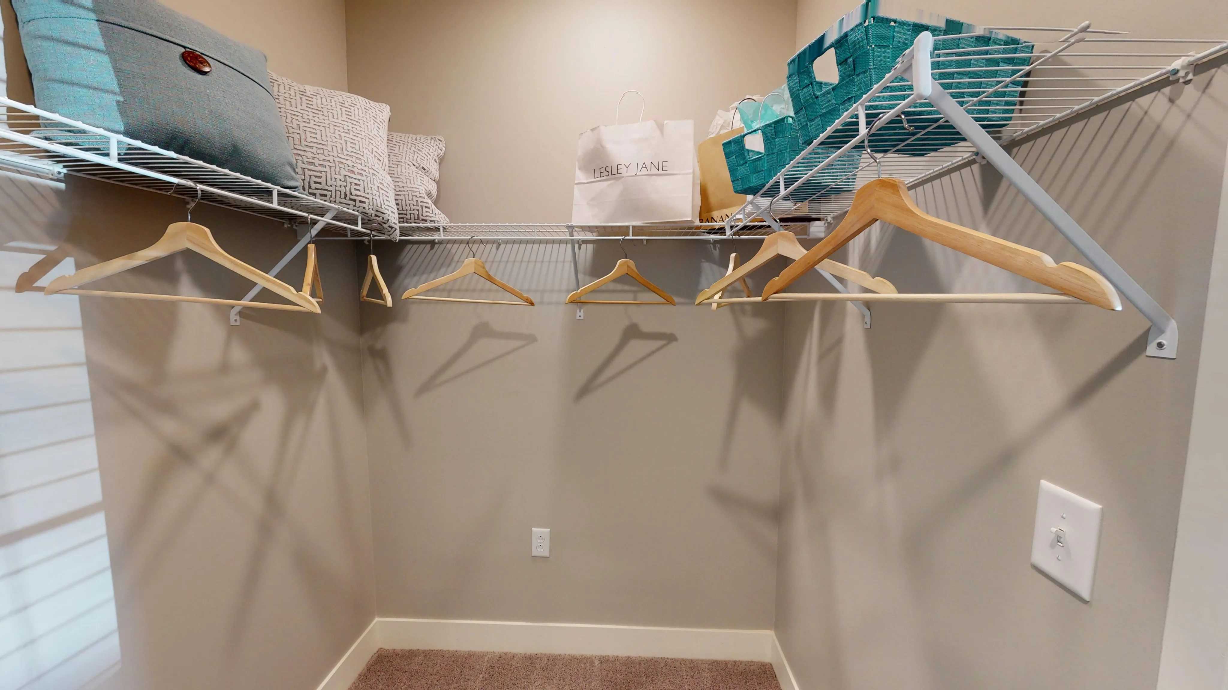 Spacious walk-in closet with organized shelving and elegant wooden hangers, ideal for maximizing storage.