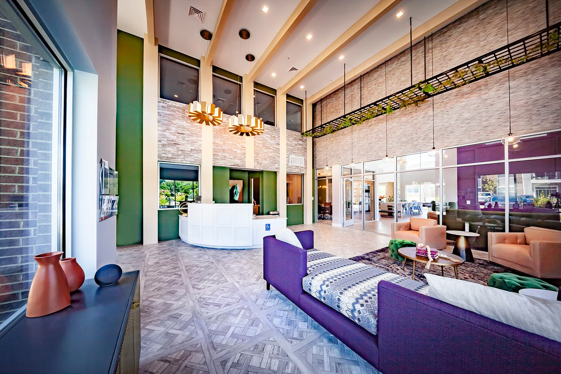 Elegant lobby with high ceilings, modern chandeliers, cozy seating, and large windows offering natural light.