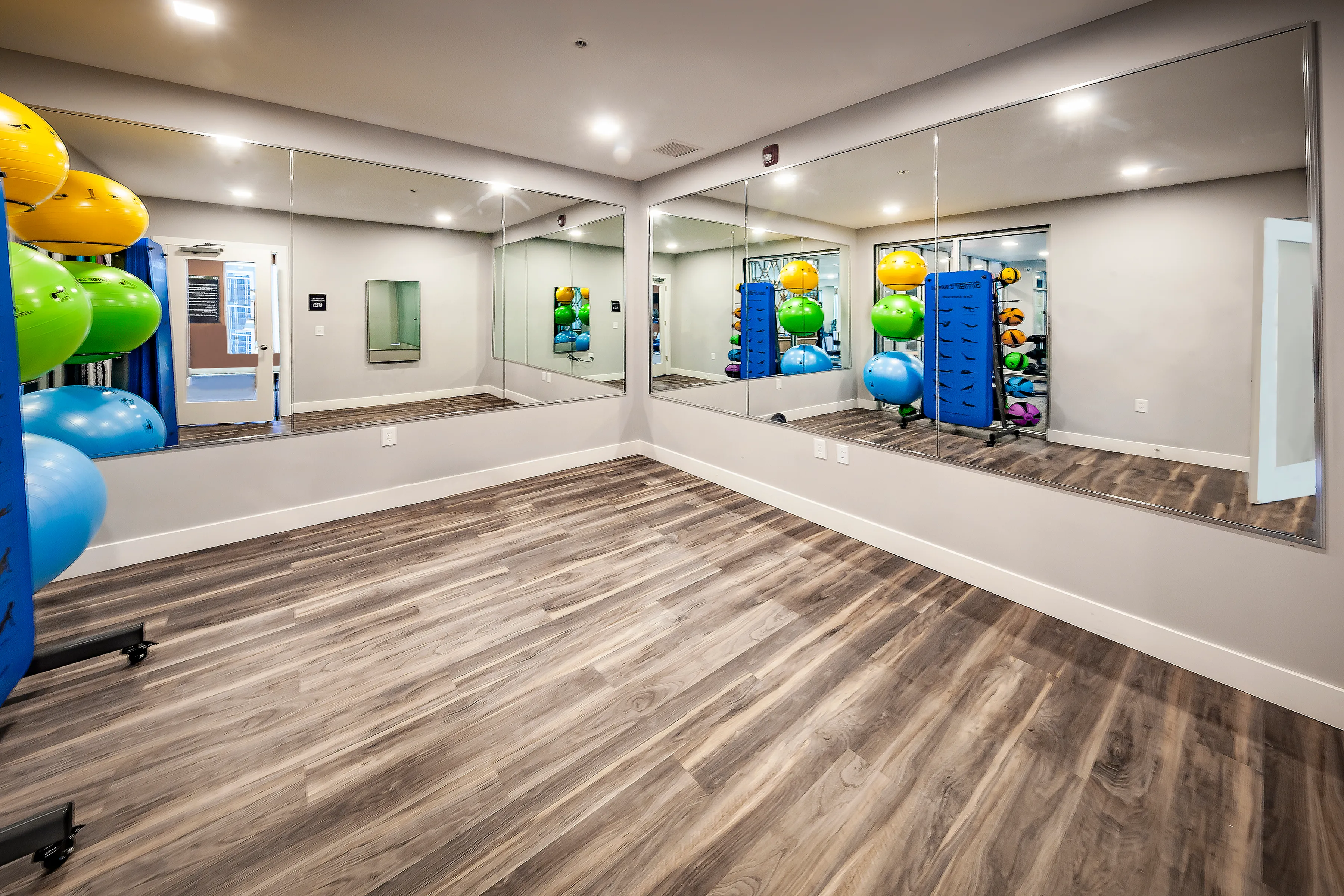 Spacious exercise room with mirrored walls and vibrant yoga balls, perfect for a dynamic workout experience.