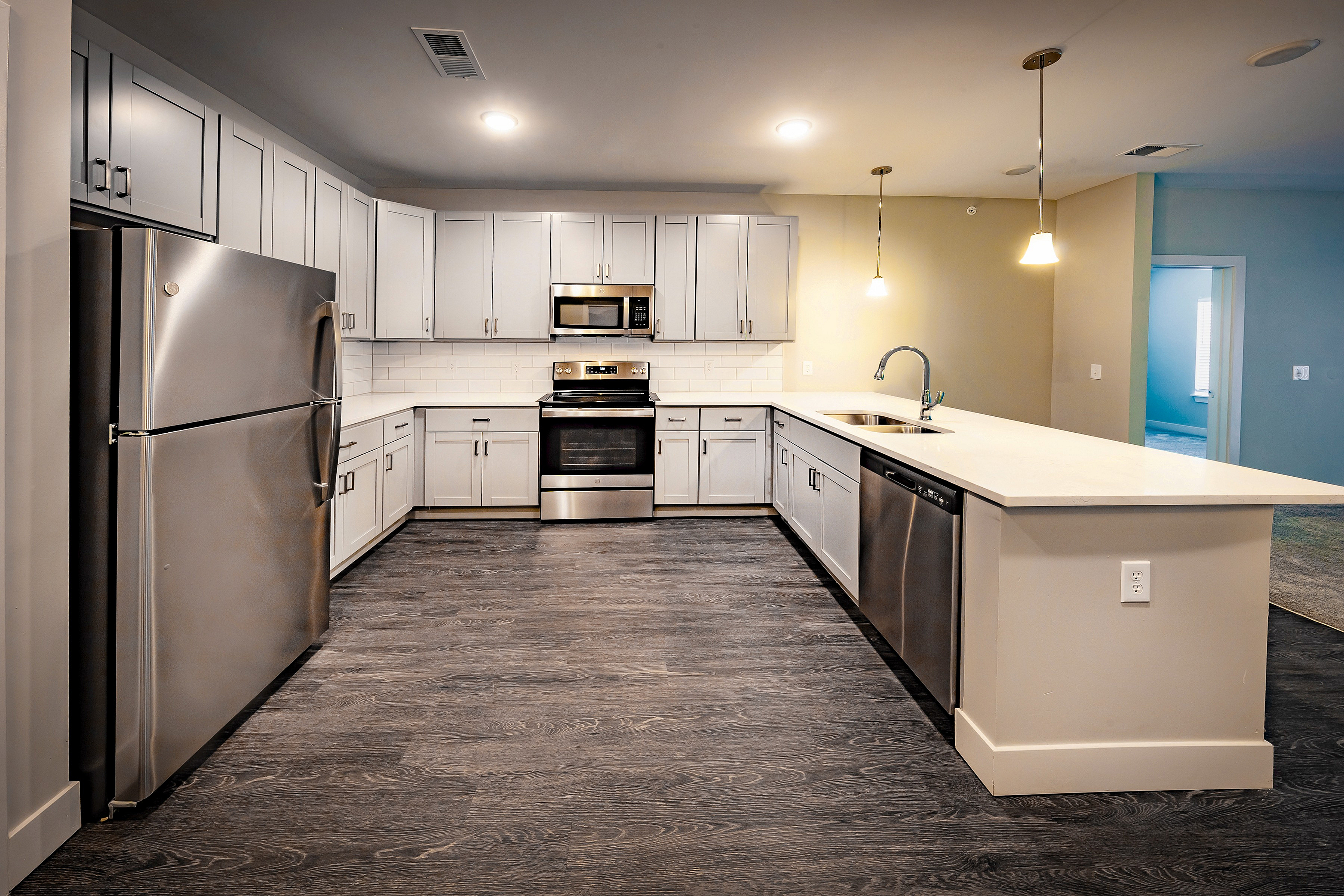 Modern kitchen with sleek stainless steel appliances, elegant white cabinetry, and stylish pendant lighting.