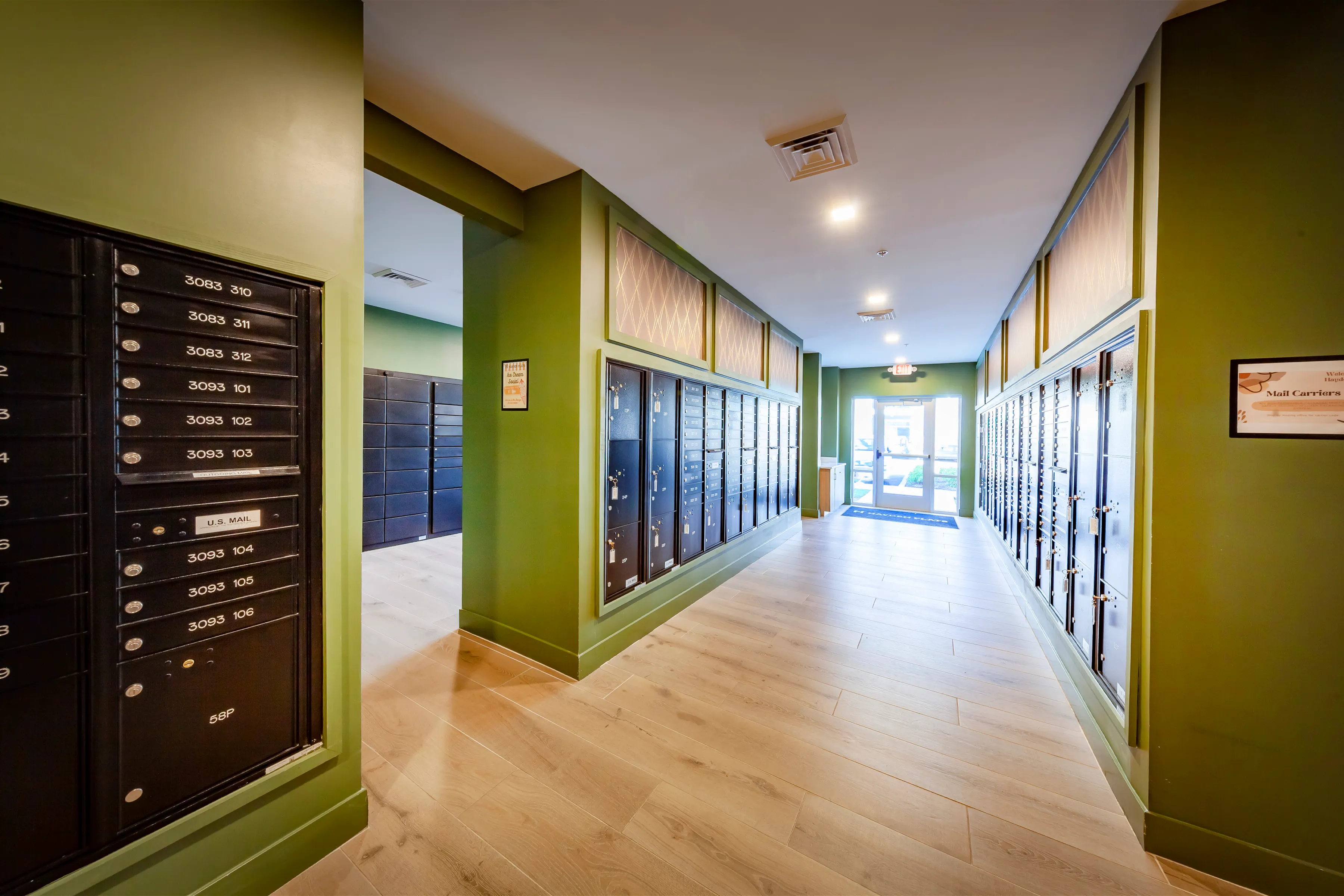 Bright and welcoming apartment lobby with sleek mailboxes and modern green accents.