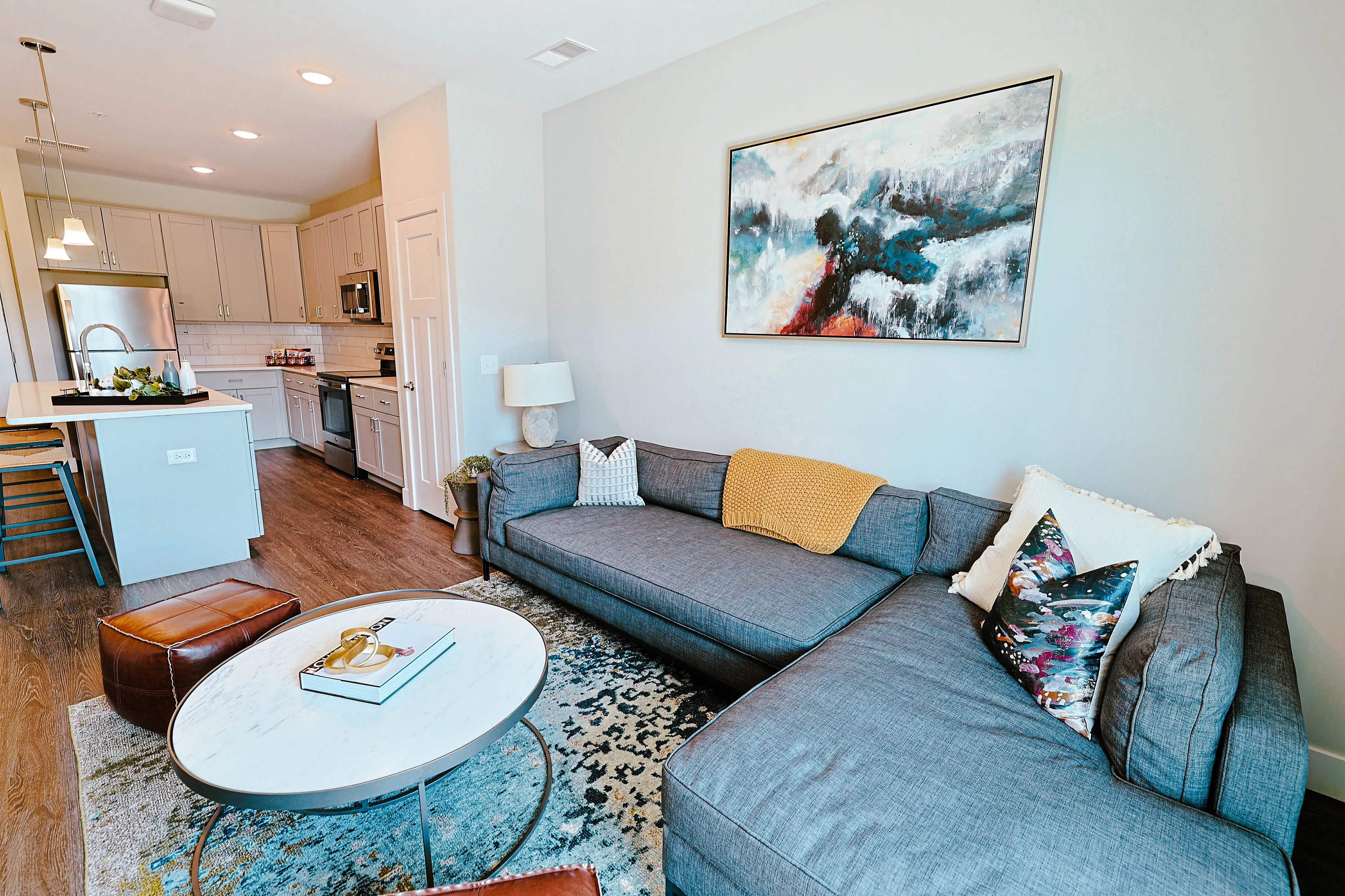 Chic open-concept living space with a modern kitchen, cozy gray sectional, and vibrant artwork, ideal for stylish urban living.