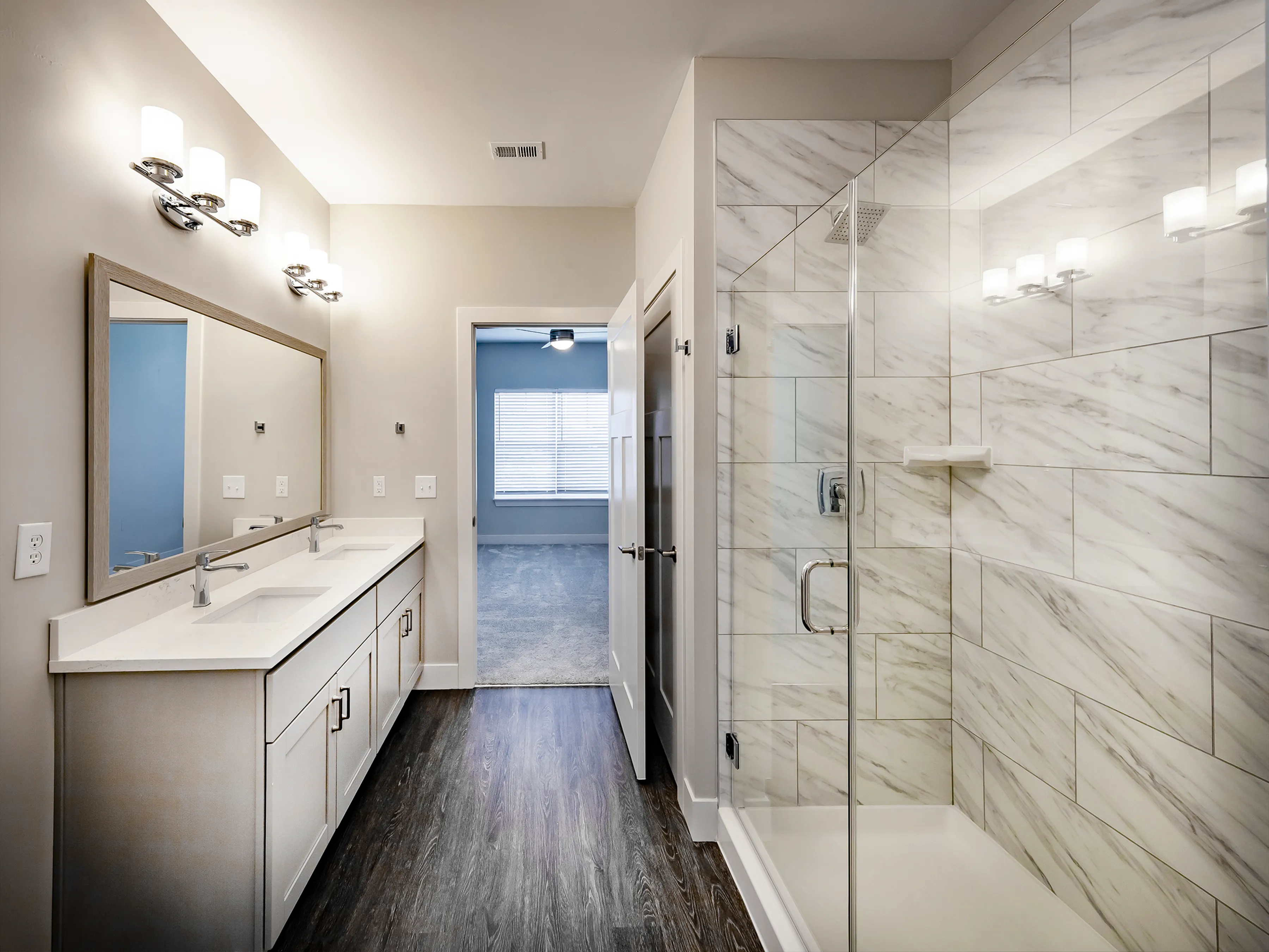 Elegant bathroom featuring a spacious double vanity and a modern glass-enclosed shower with marble tilework.