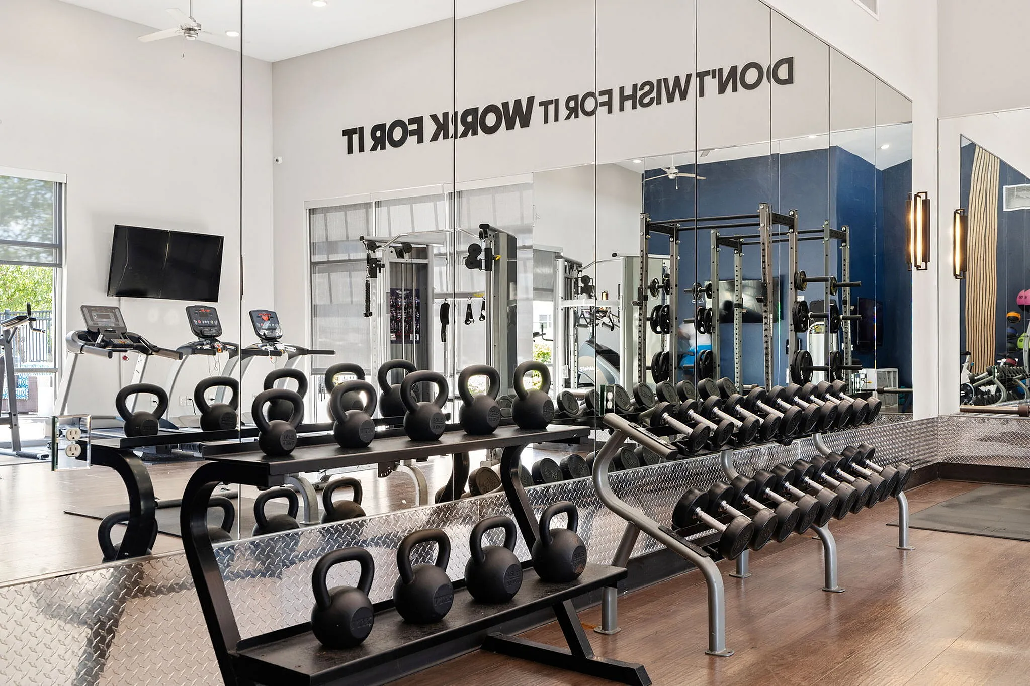Modern gym with sleek design featuring treadmills, kettlebells, and a full set of dumbbells for an invigorating workout experience.