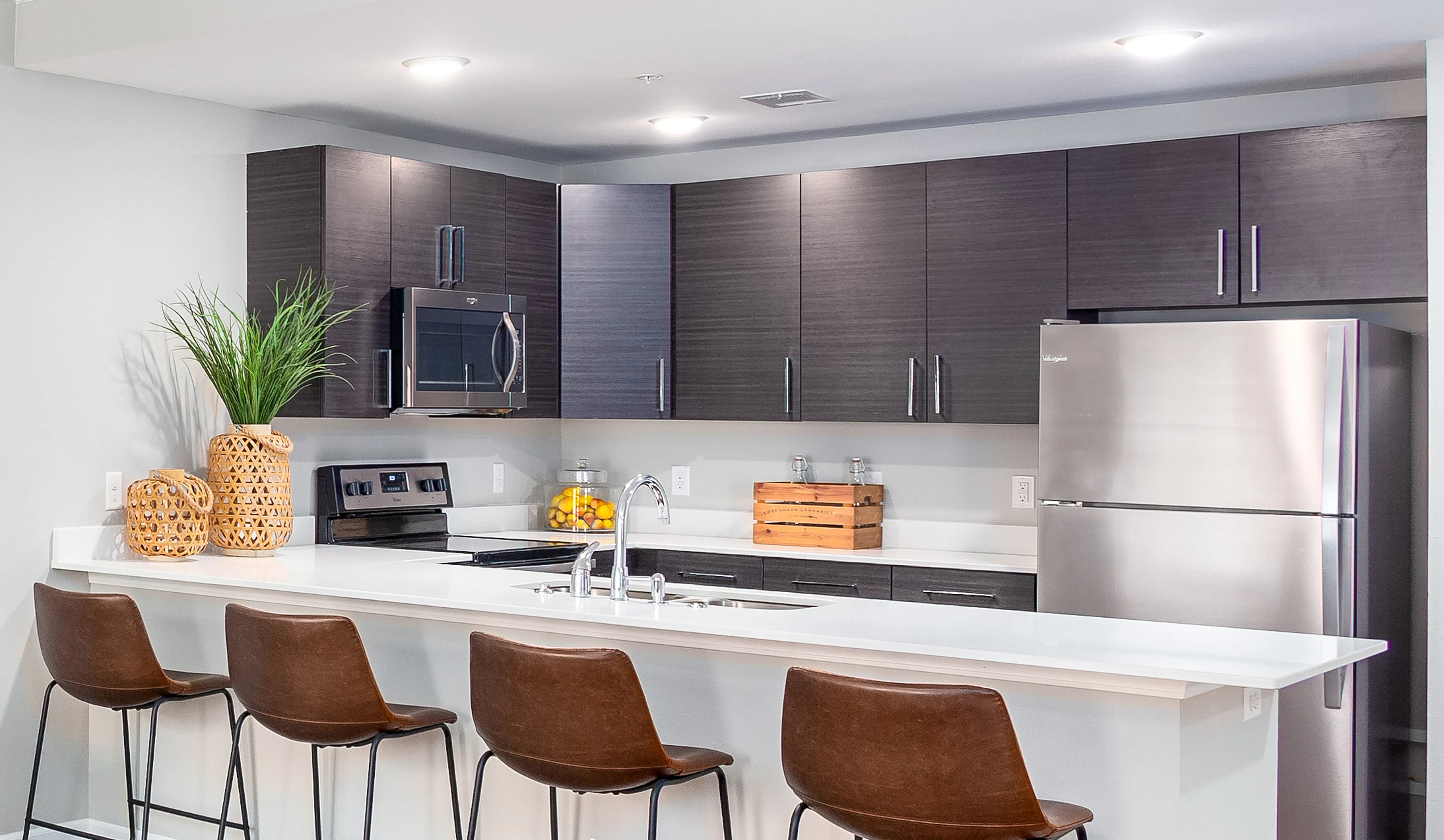 Modern kitchen with sleek dark cabinetry, stainless steel appliances, and a stylish island with chic bar seating.