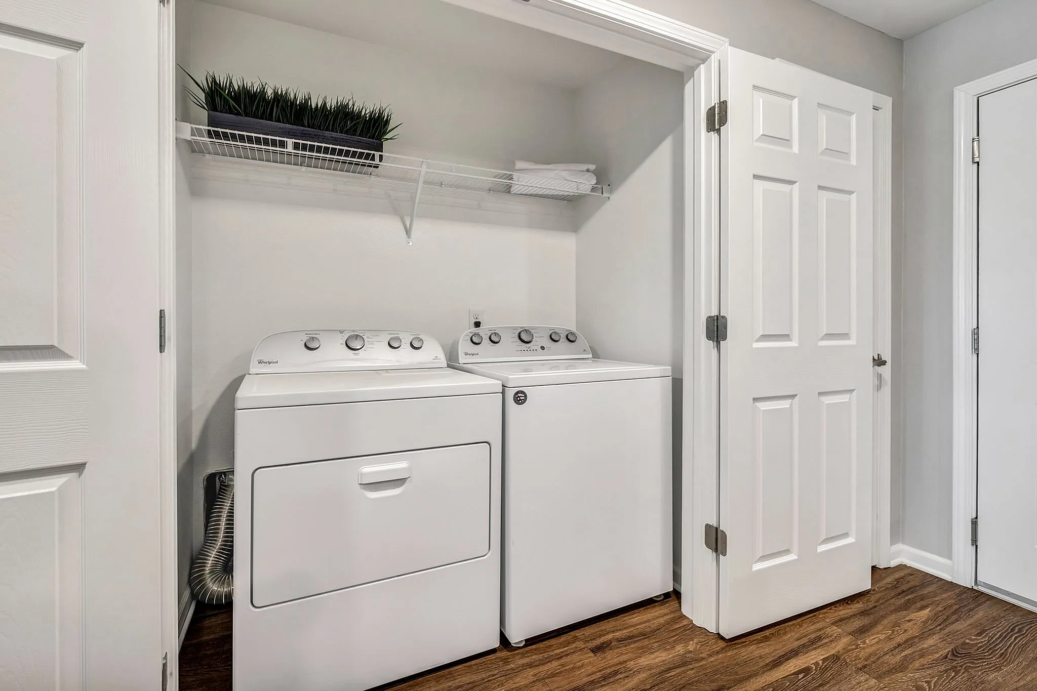 Modern laundry area with sleek washer and dryer, featuring elegant white doors and a stylish wood floor.