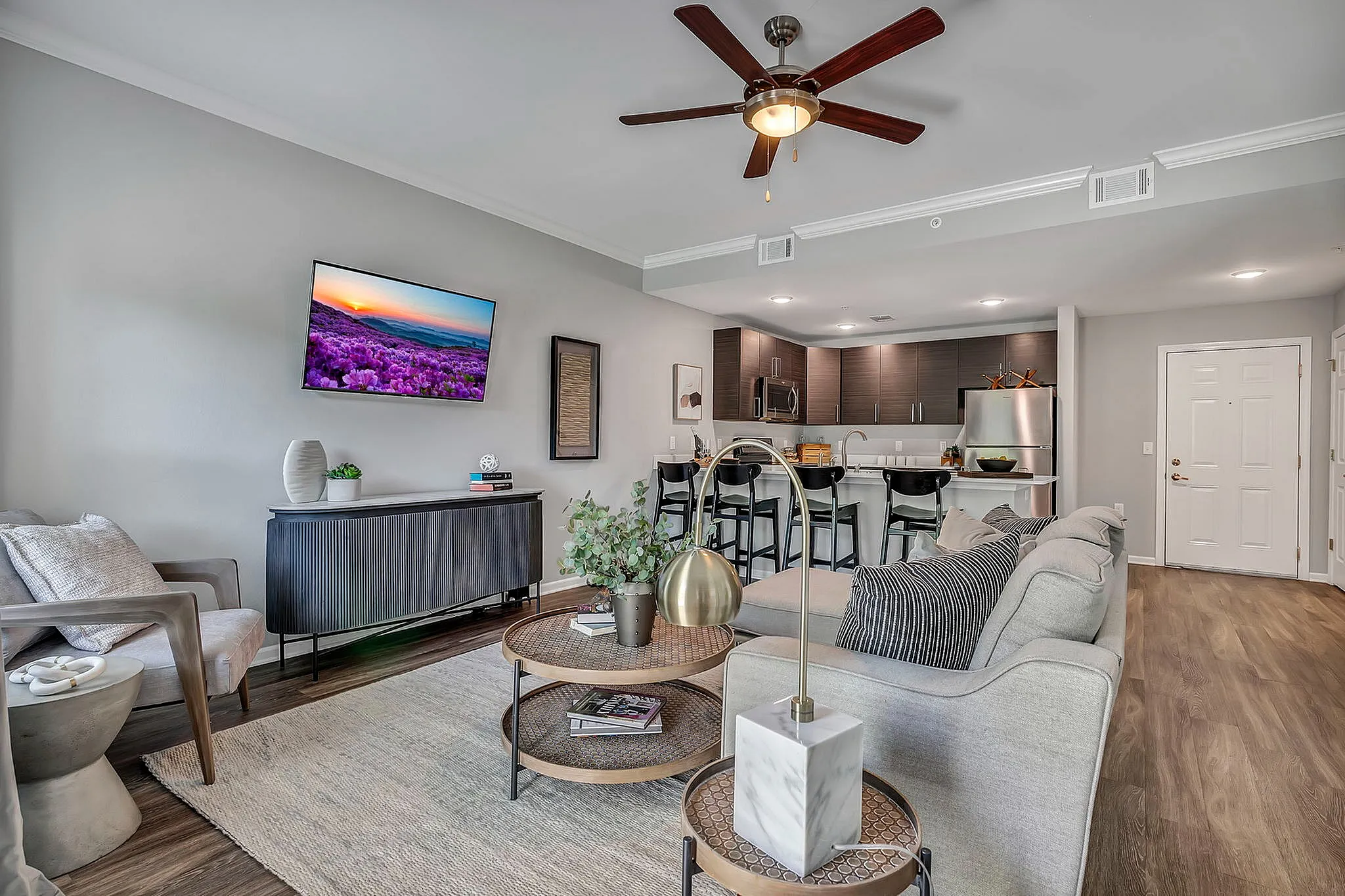 Modern living room with cozy seating, stylish decor, and an open-plan kitchen featuring sleek cabinetry and a breakfast bar.