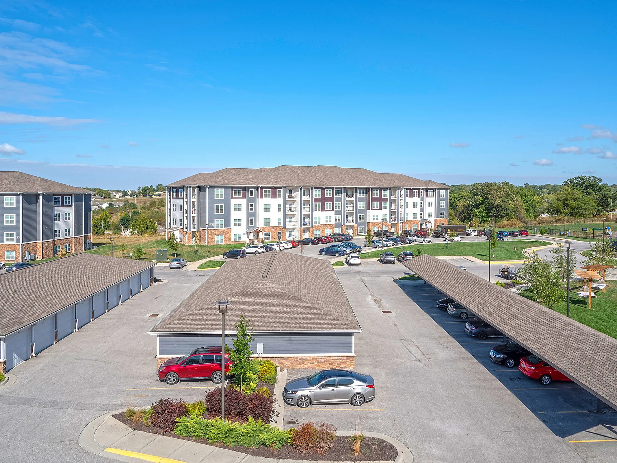 Inviting apartment complex with modern architecture featuring spacious parking and lush green surroundings, perfect for comfortable living.