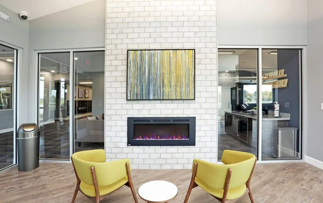 Modern apartment lounge with a sleek fireplace, bright yellow chairs, and artistic decor creating a cozy, stylish atmosphere.