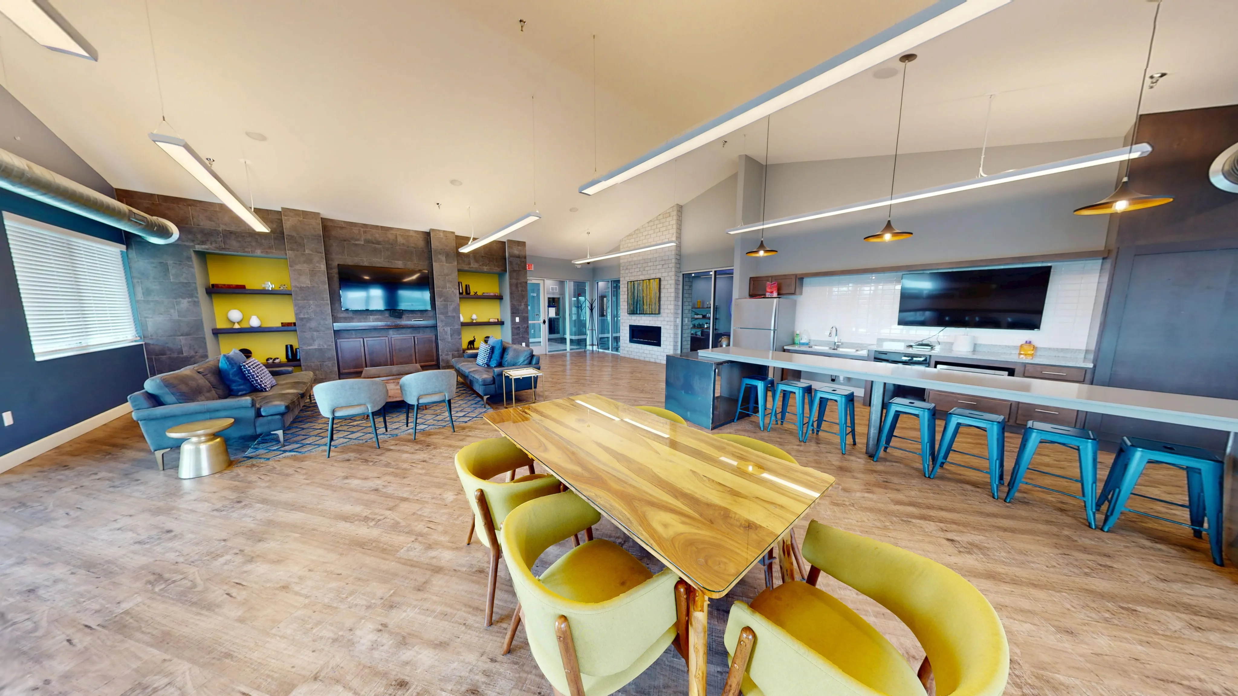 Elegant open-concept living area with cozy seating, stylish wooden dining table, modern kitchen, and large TV, showcasing contemporary design and vibrant decor.