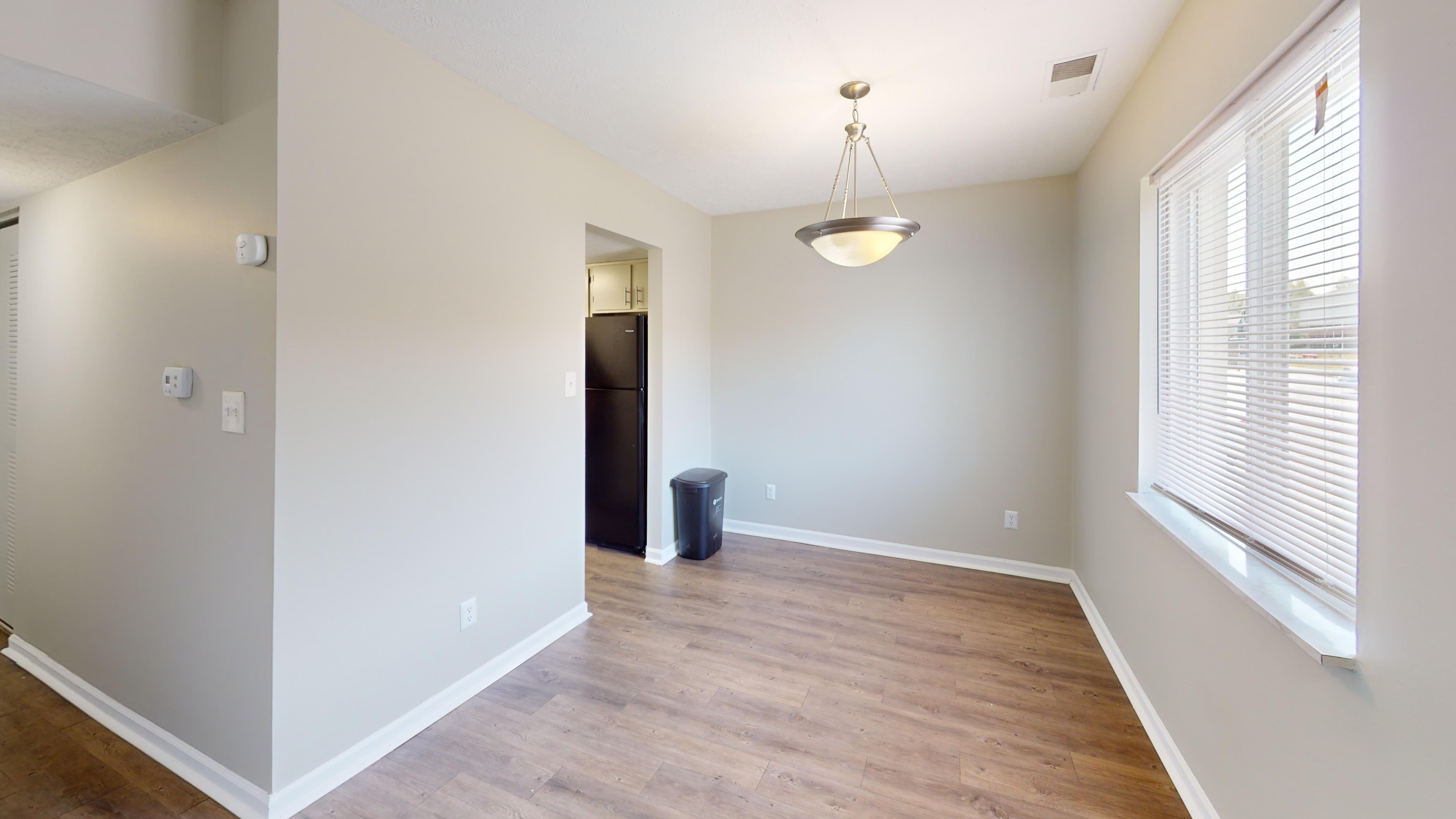 Bright dining area with elegant lighting, hardwood floors, and a large window offering plenty of natural light.