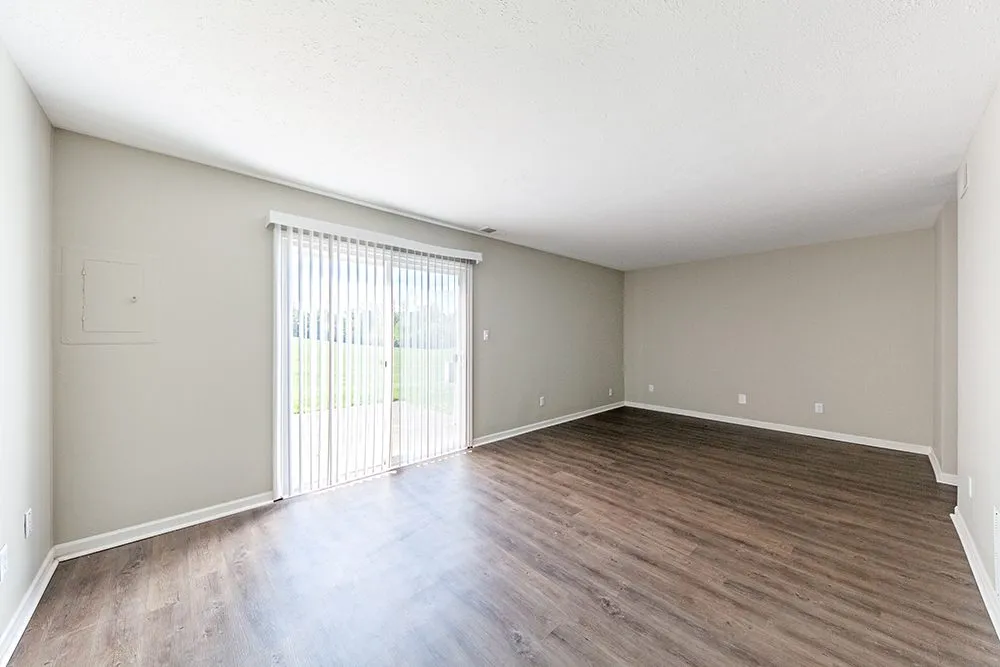 Bright and spacious living room with elegant wood flooring and large sliding glass doors opening to a scenic outdoor view.