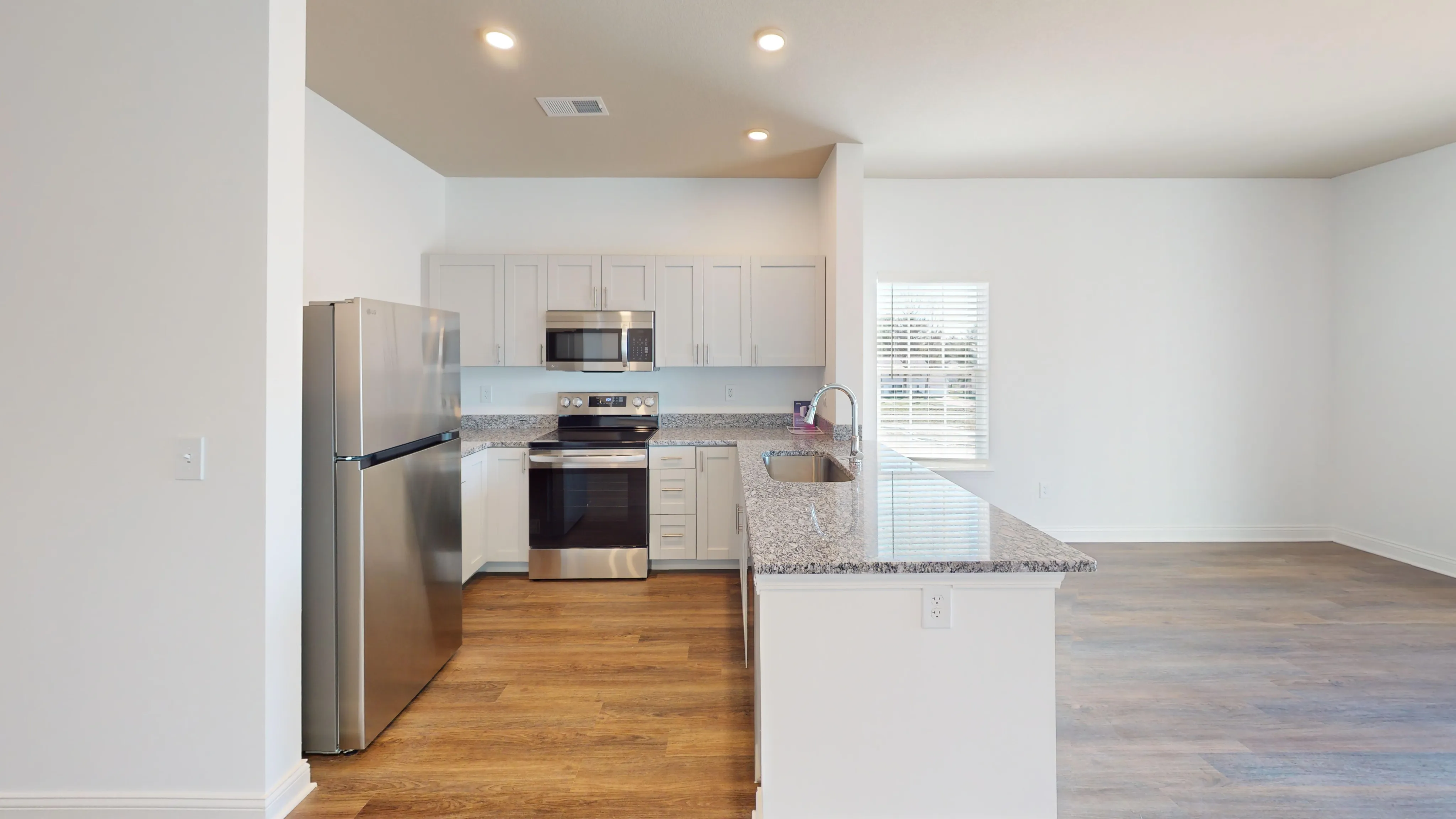 Bright open-concept living room and modern kitchen with stainless steel appliances.
