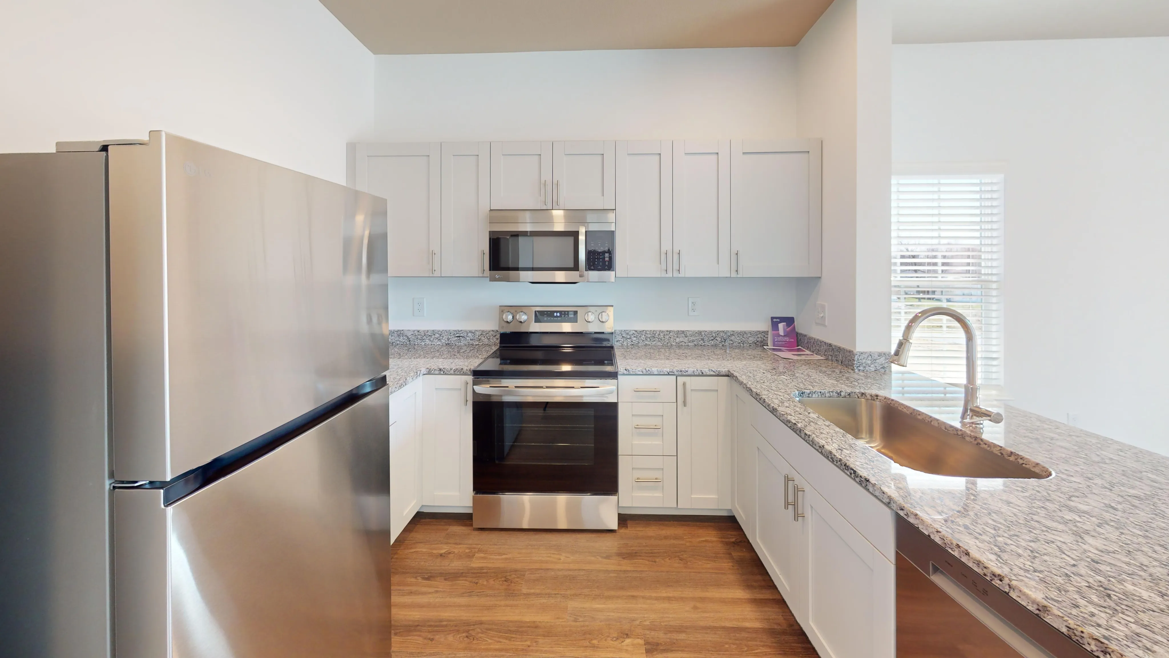 Bright and airy modern kitchen with granite counters and stainless steel appliances.