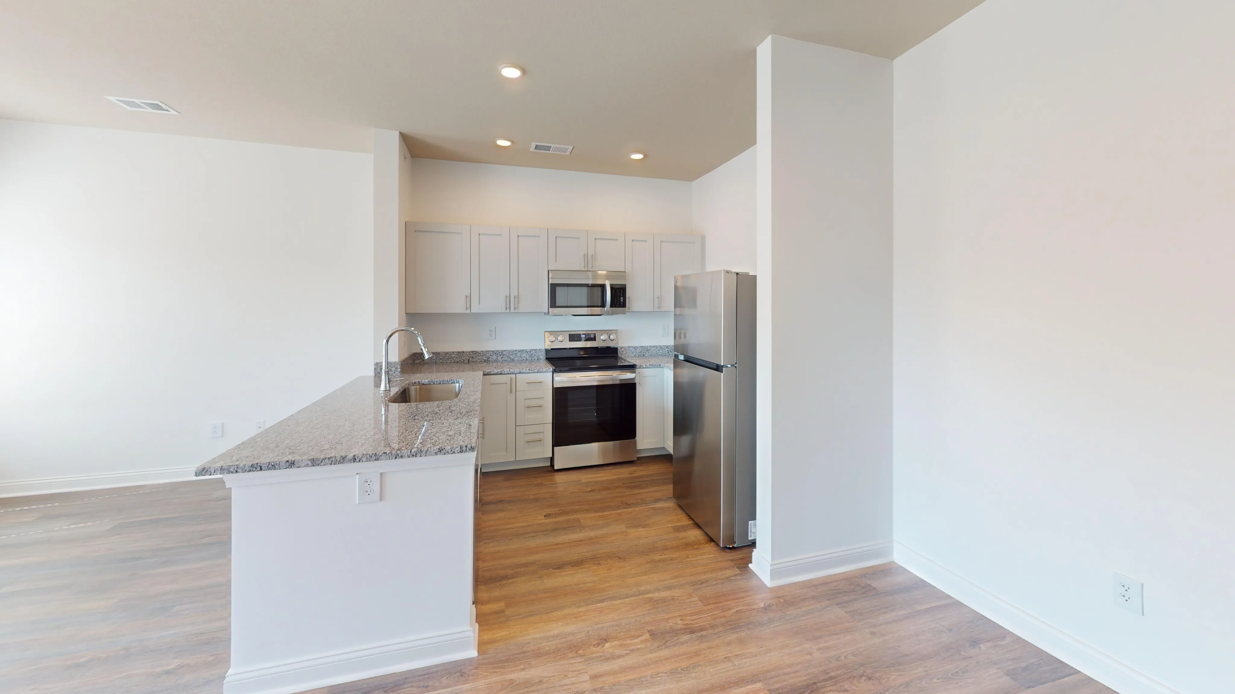 Modern kitchen with sleek granite countertops, stainless steel appliances, and elegant wood flooring.