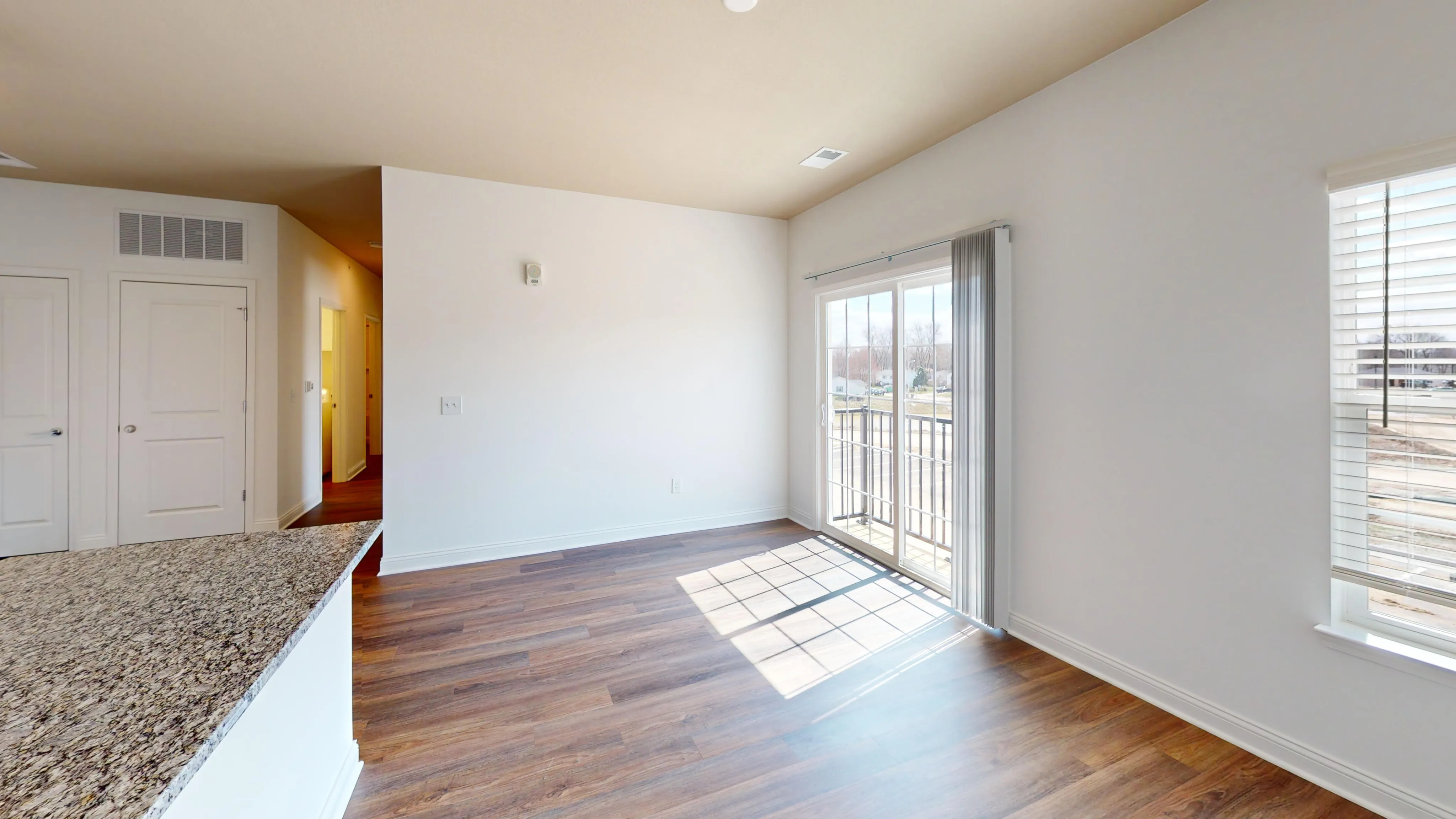 Bright and spacious living area with sleek hardwood floors and large sliding doors leading to a sunny balcony.