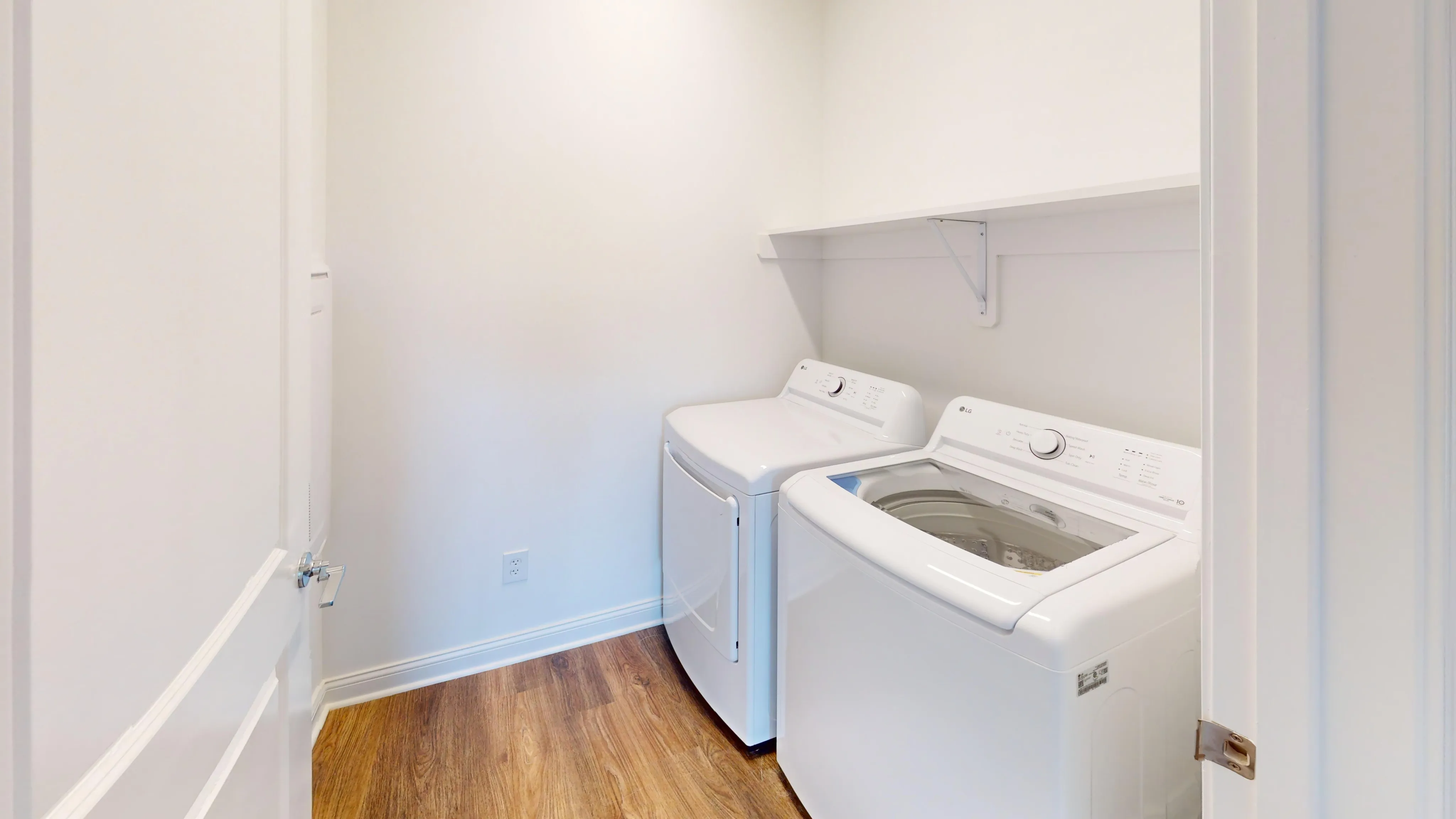Bright laundry room with modern washer and dryer, featuring warm wood flooring and a clean, minimalist design.