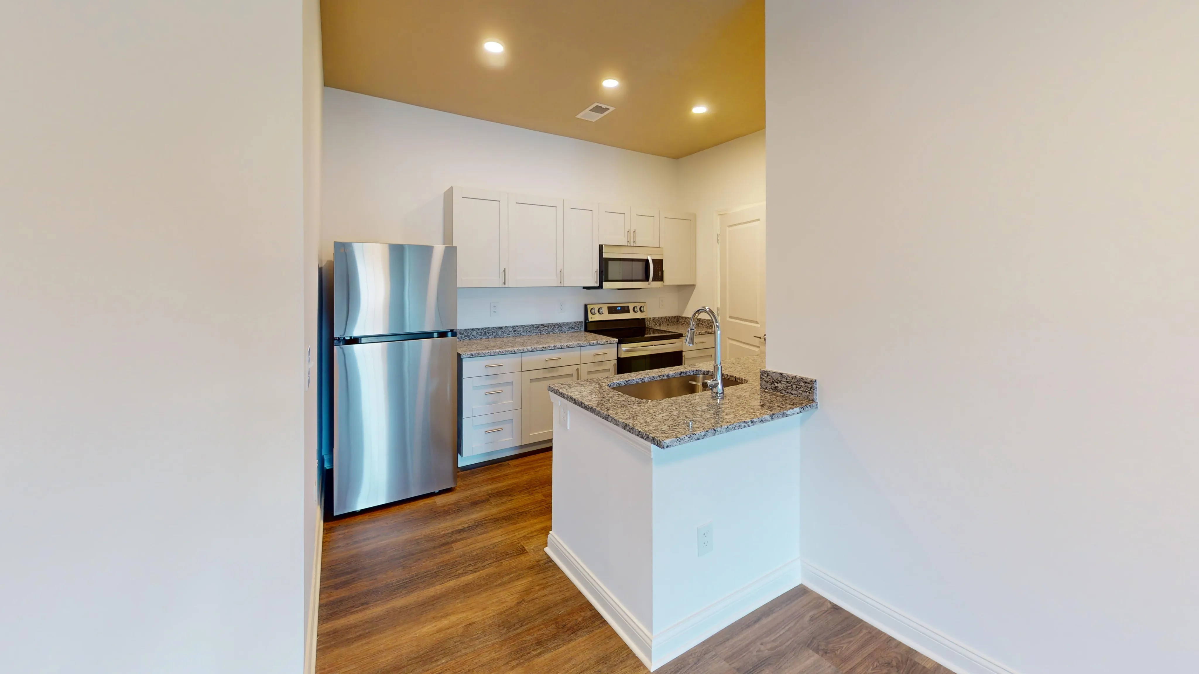 Modern kitchen with sleek stainless steel appliances, granite countertops, and elegant wooden flooring.