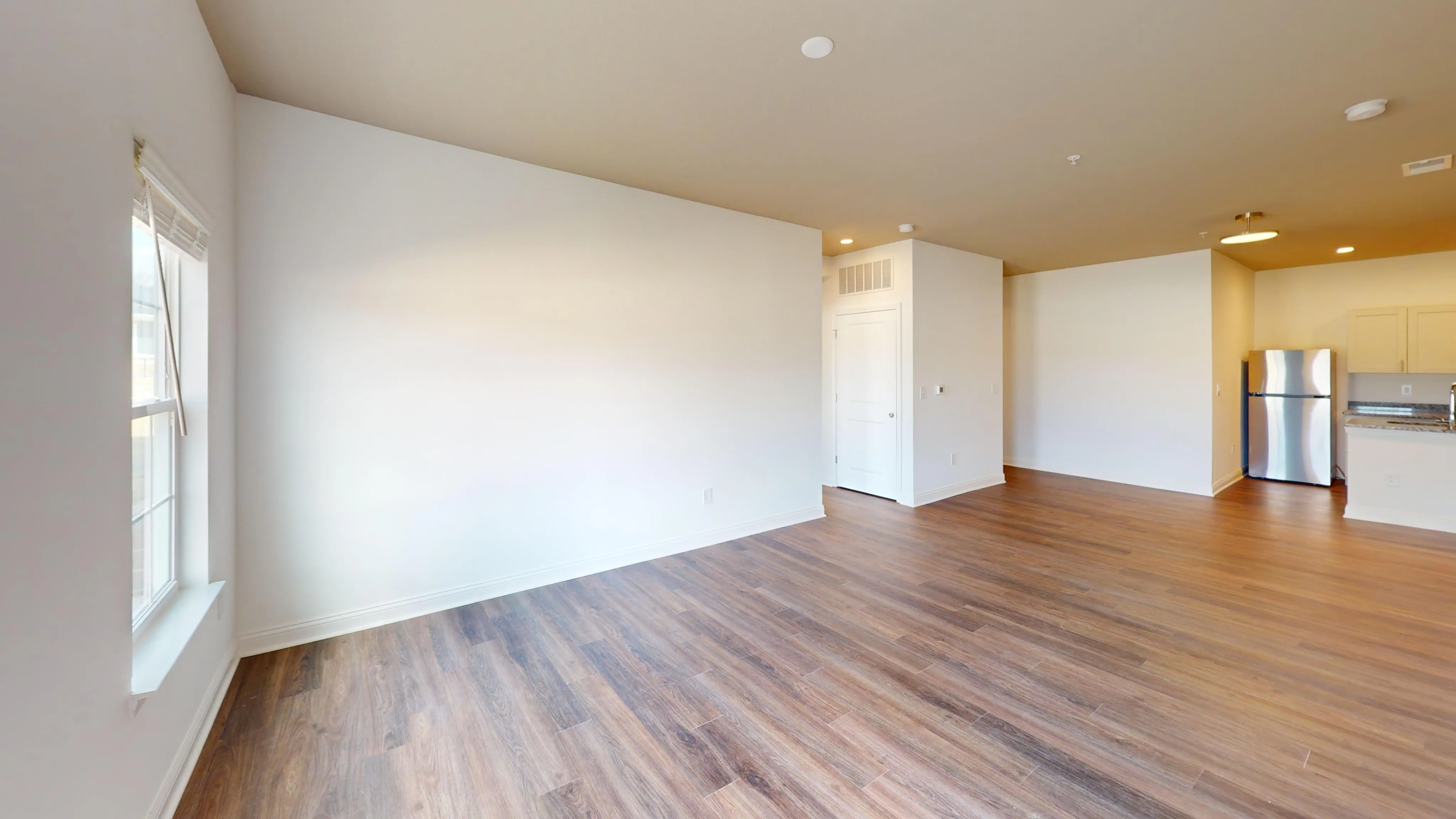 Modern open-floor apartment with sleek hardwood floors, abundant natural light, and stainless steel appliances in the kitchen.