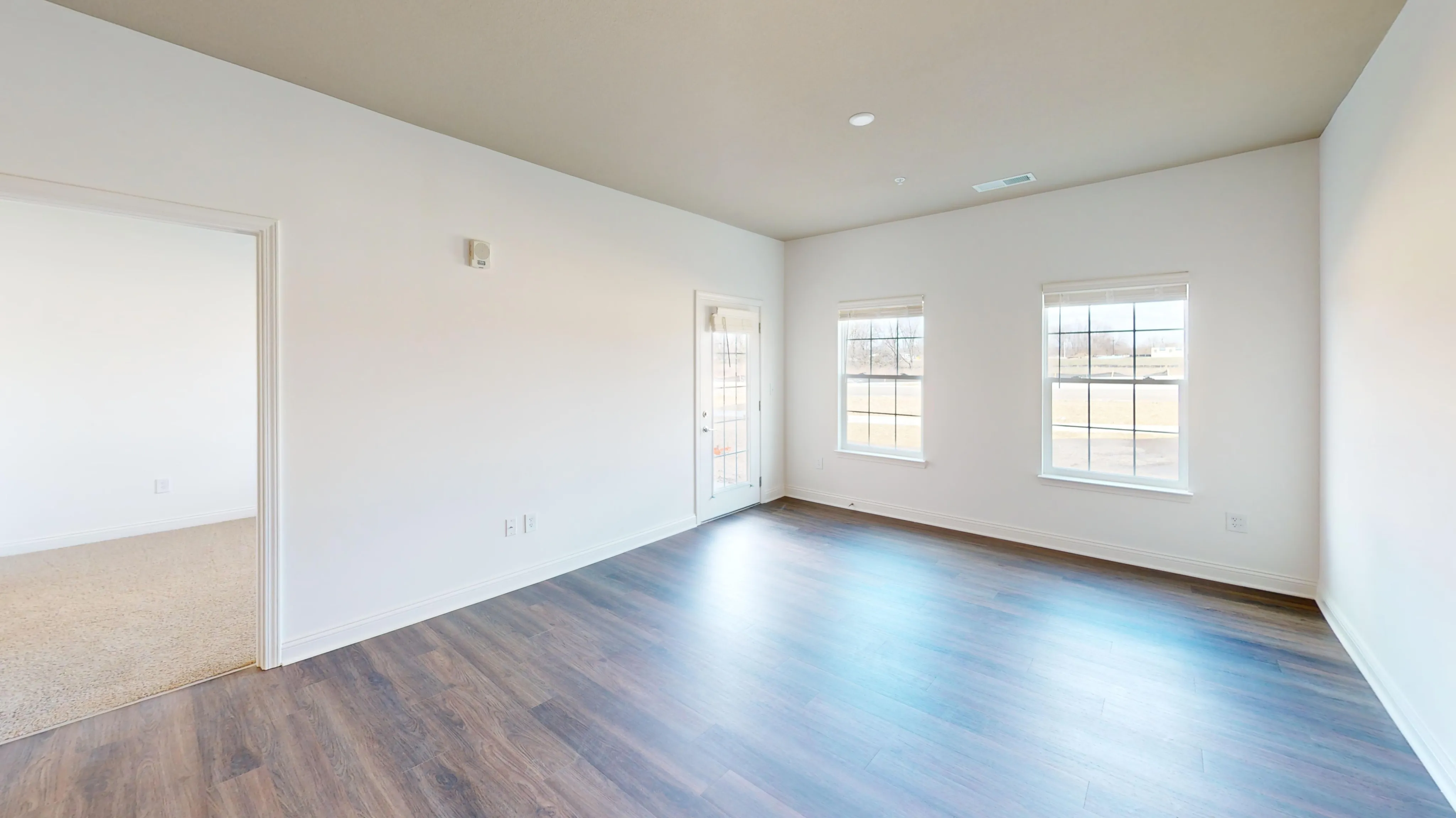 Bright and inviting living space with large windows and elegant wooden flooring, perfect for modern living.
