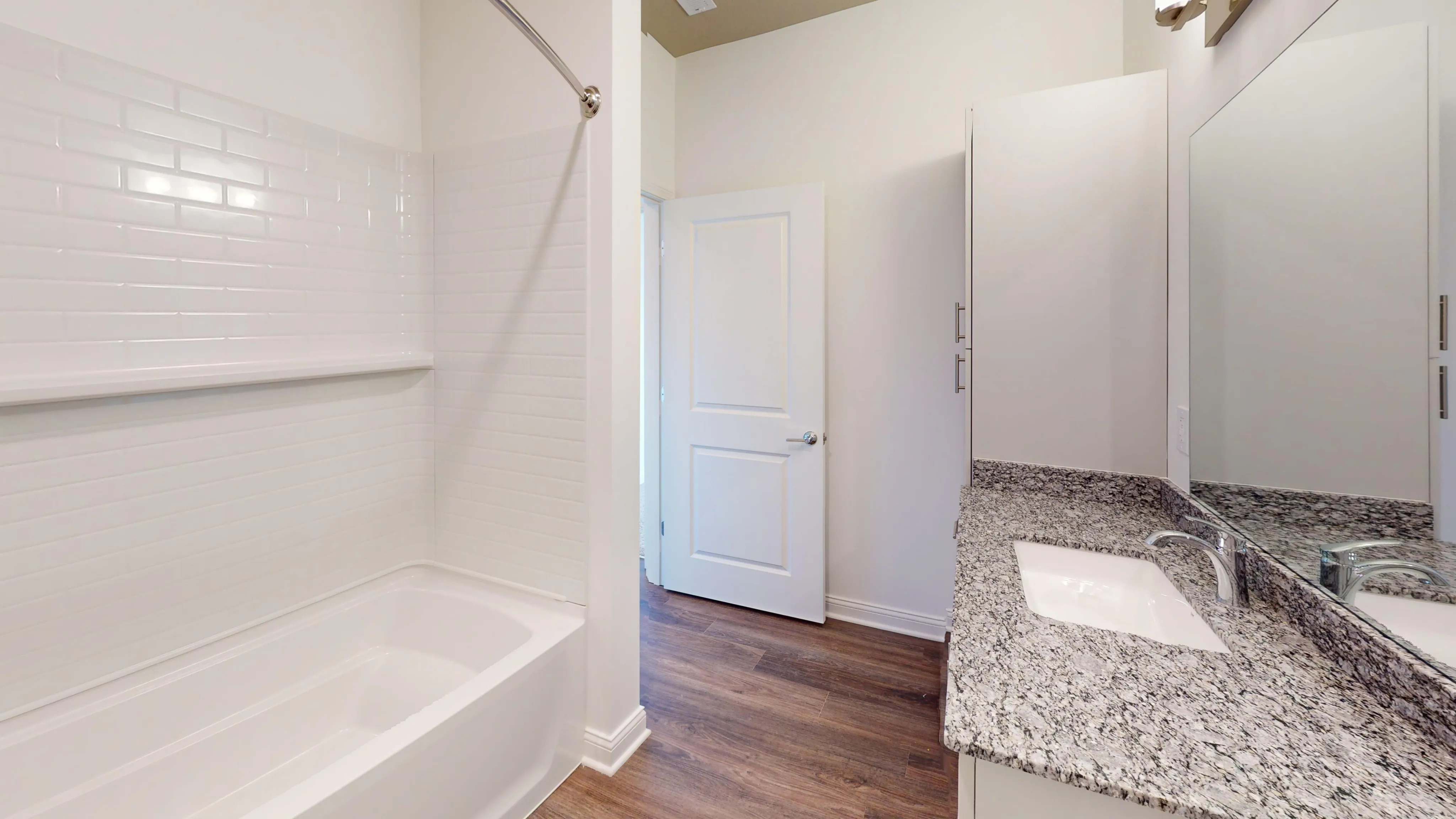Modern bathroom with granite countertop, sleek sink, and luxurious tub in a bright, elegant setting.