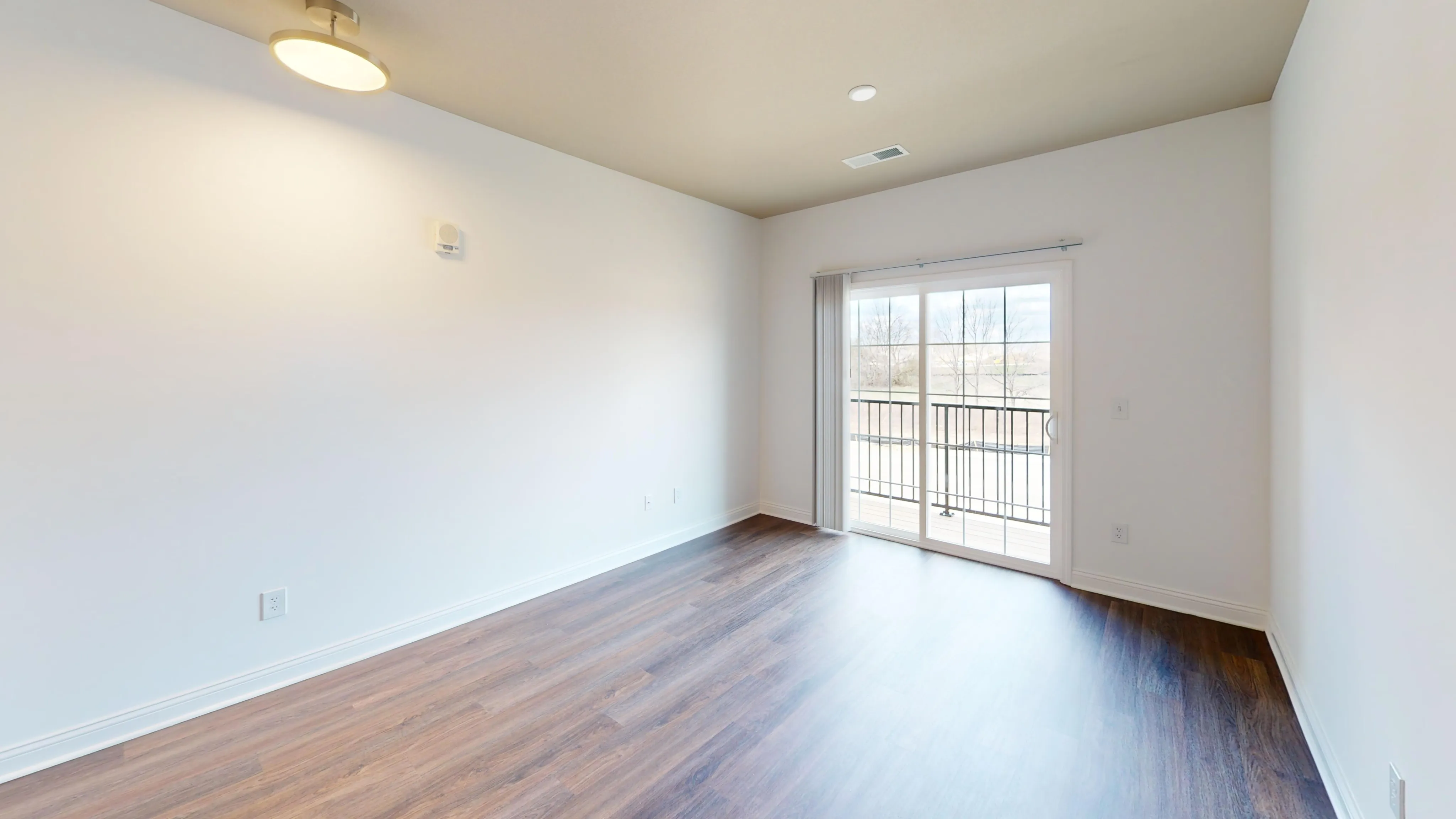 Bright and airy living room featuring hardwood floors and a sliding glass door to a private balcony.