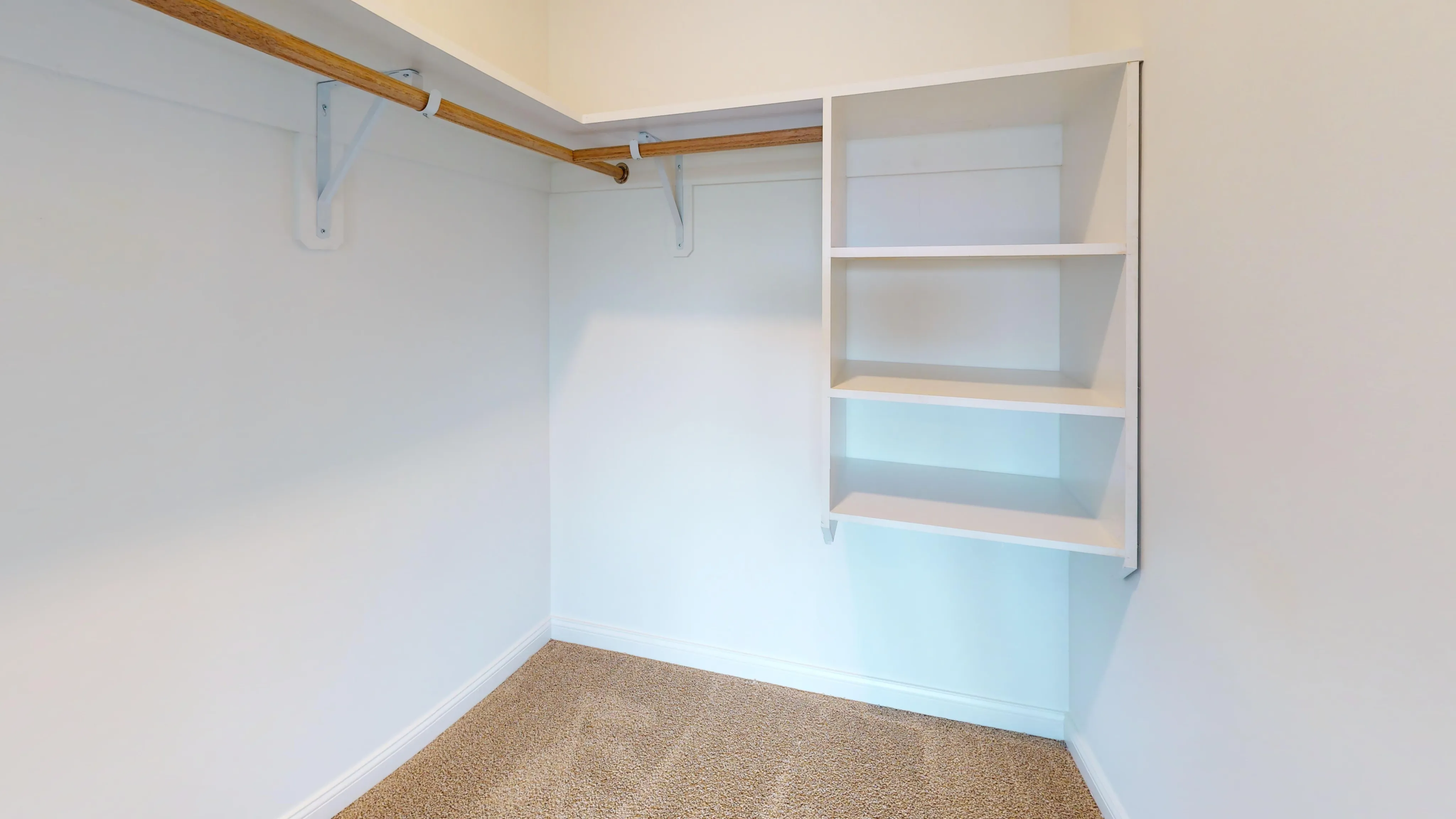 Spacious walk-in closet with built-in shelving and hanging rod, perfect for organized storage.