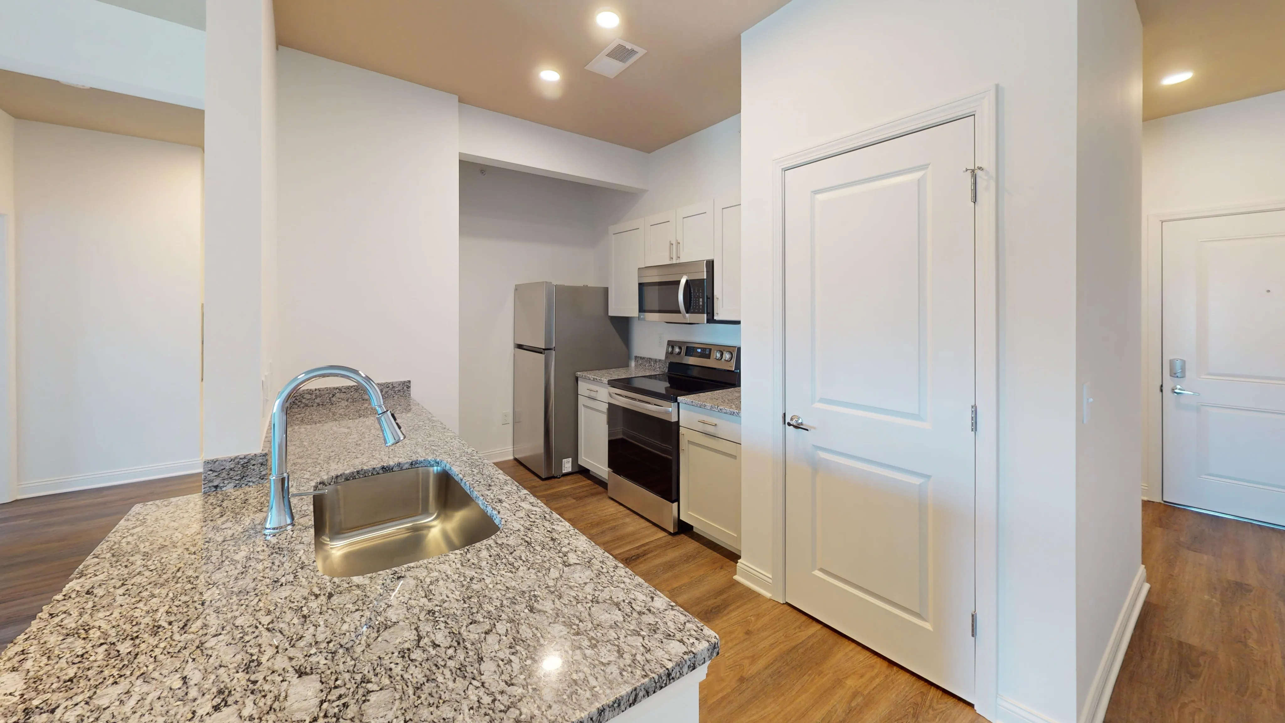Modern kitchen with stainless steel appliances, granite countertops, and elegant recessed lighting.