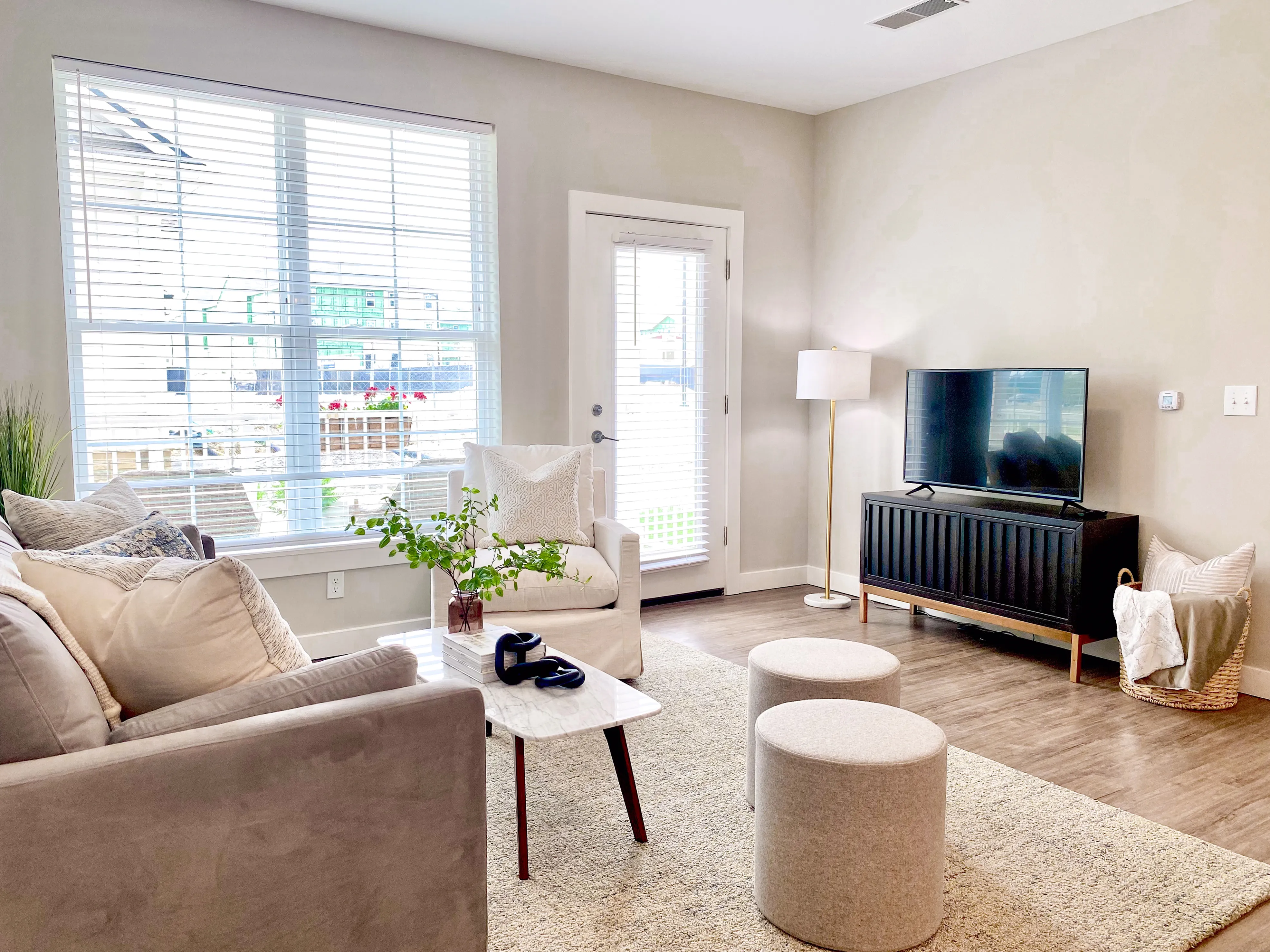 Bright and inviting living room with modern decor, cozy seating, and large window overlooking a patio.