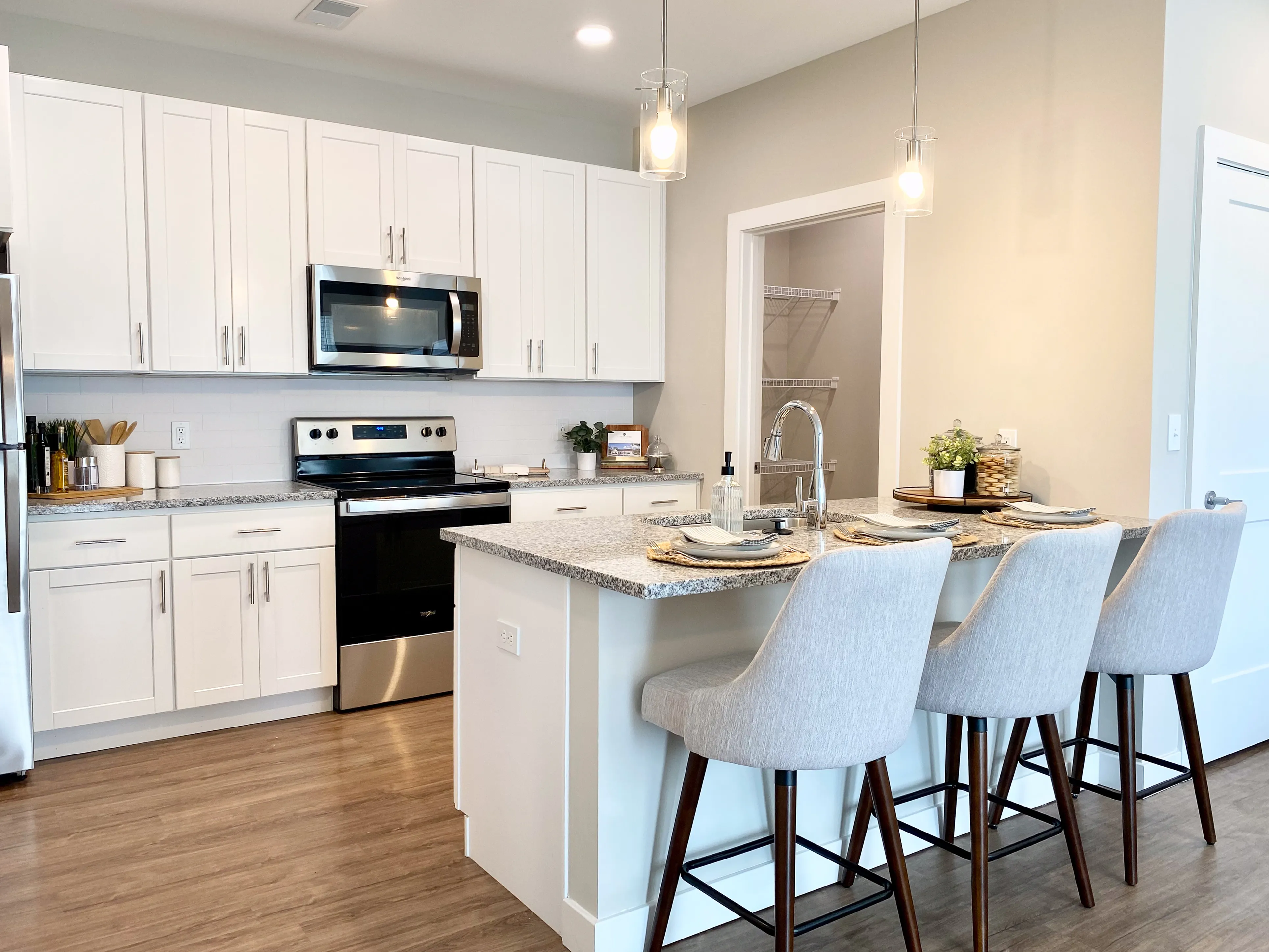 Contemporary kitchen with sleek white cabinetry, granite countertops, and a stylish island with seating for four, perfect for entertaining.
