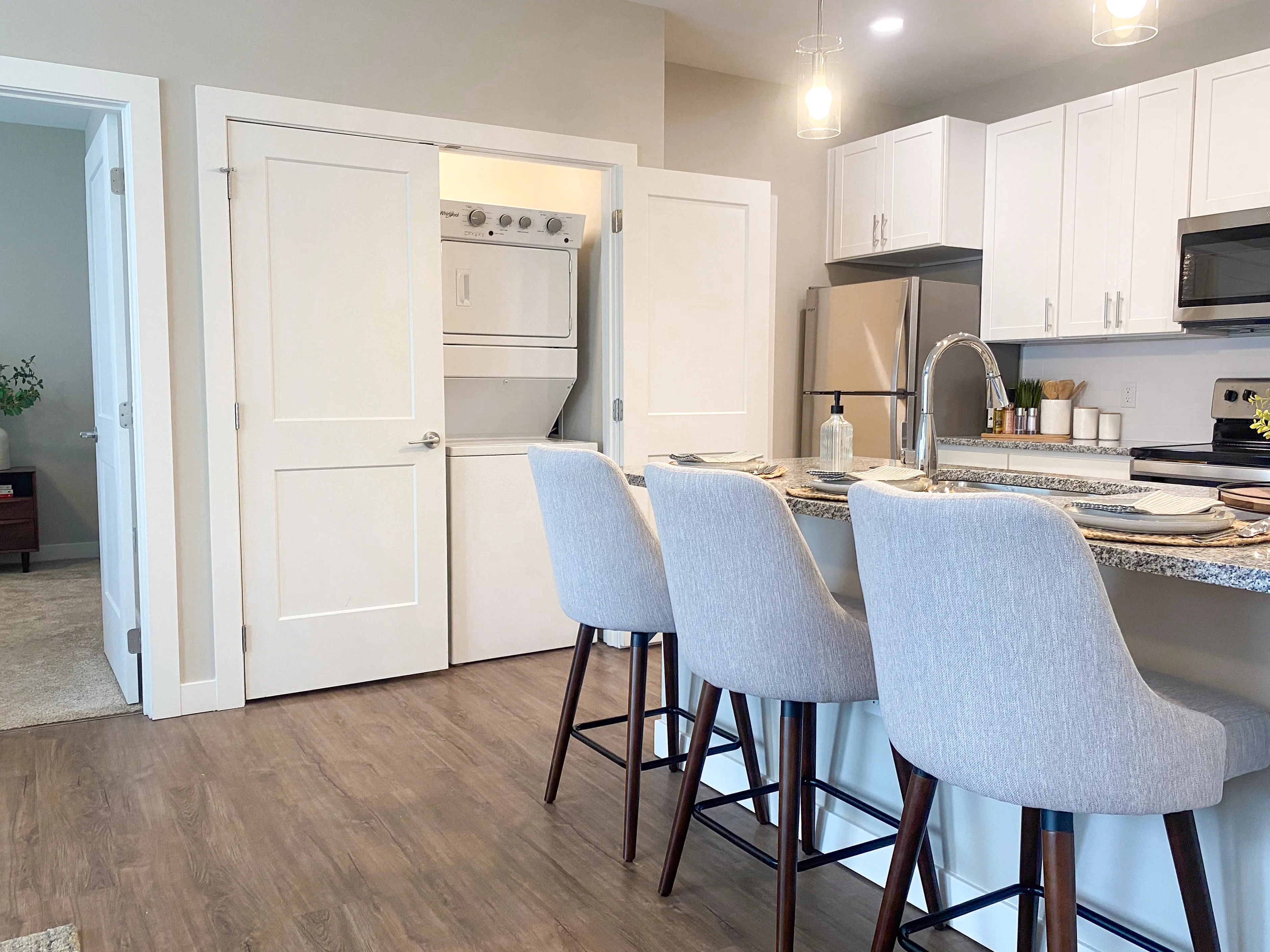 Modern kitchen with sleek granite countertops, elegant bar seating, and in-unit laundry tucked away for convenience.