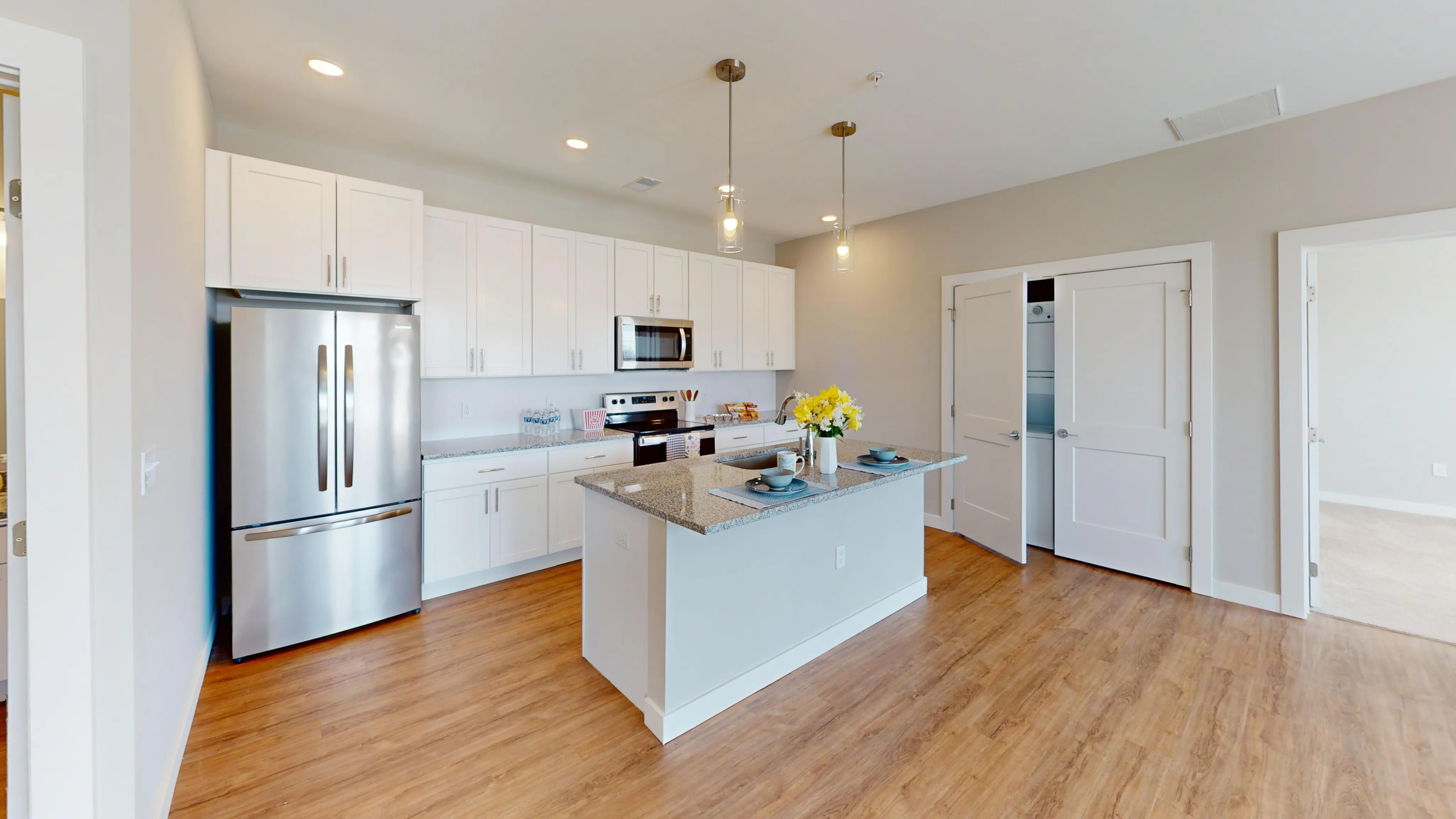 Bright and modern kitchen with sleek stainless steel appliances, elegant white cabinetry, and a stylish granite island with breakfast bar.