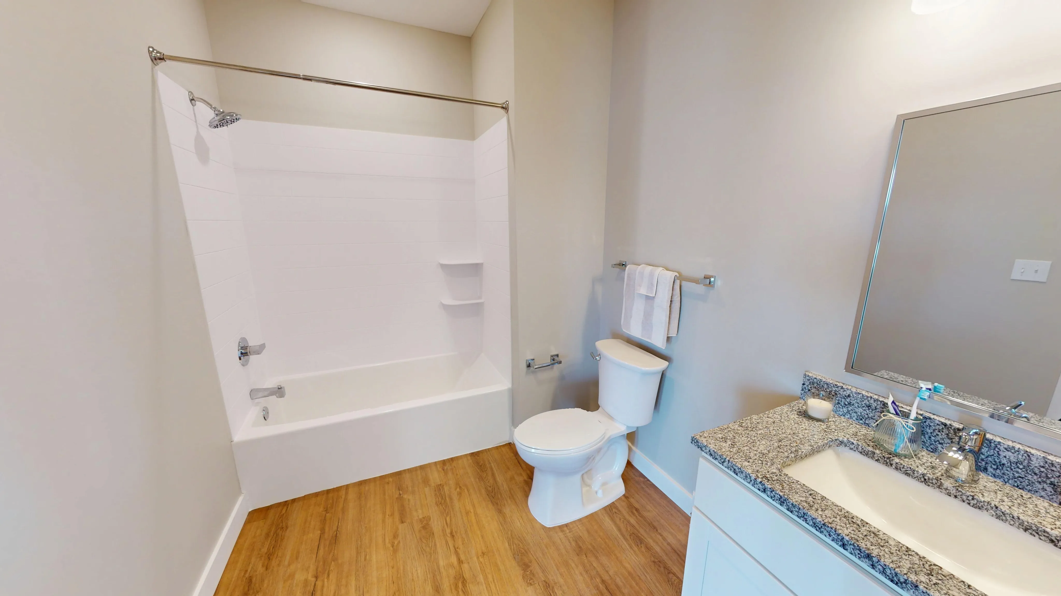 Modern bathroom with sleek granite countertop, elegant cabinetry, and bright wooden flooring.