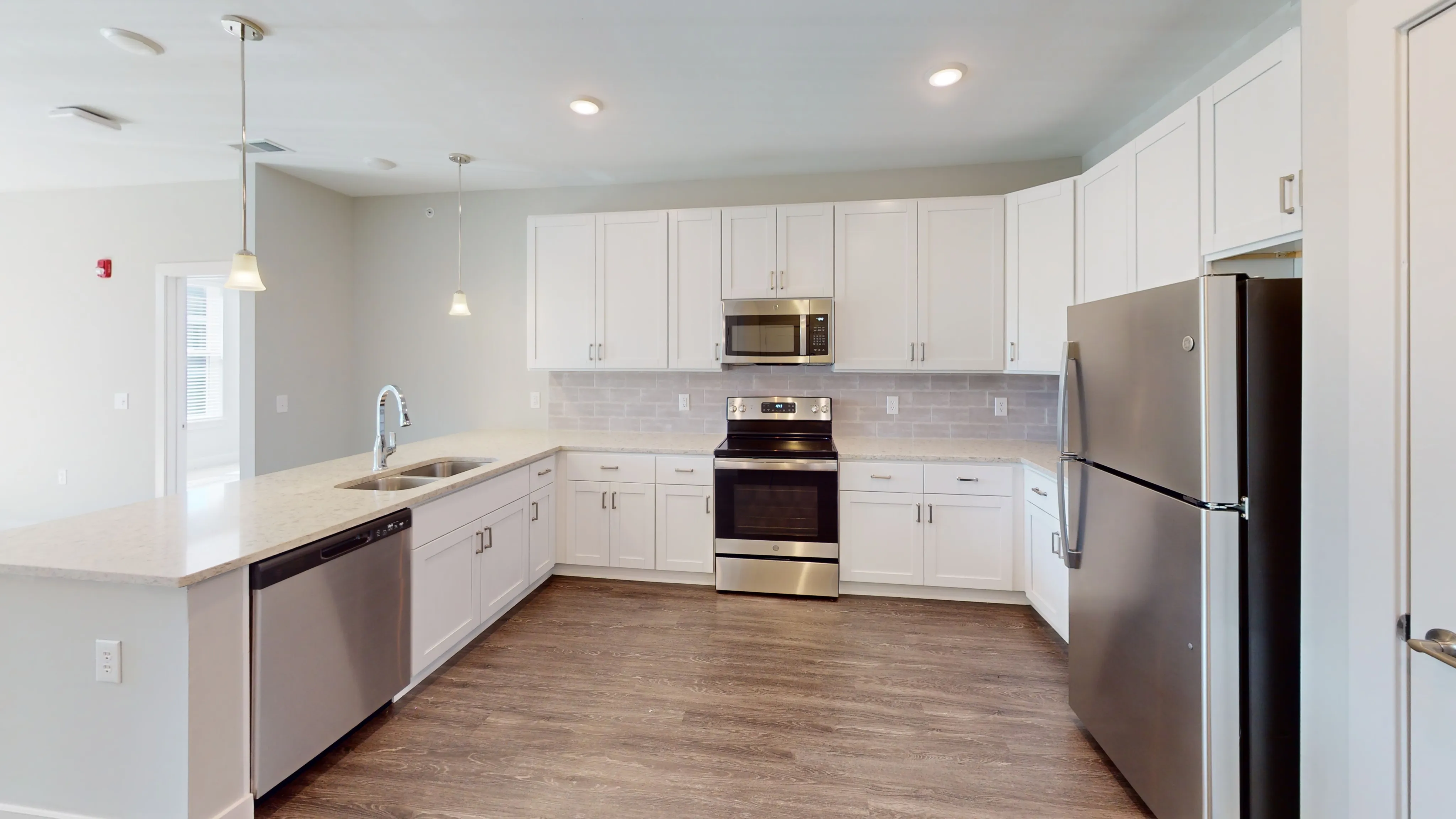 Modern kitchen with sleek stainless steel appliances, white cabinetry, and elegant pendant lighting over a spacious island.