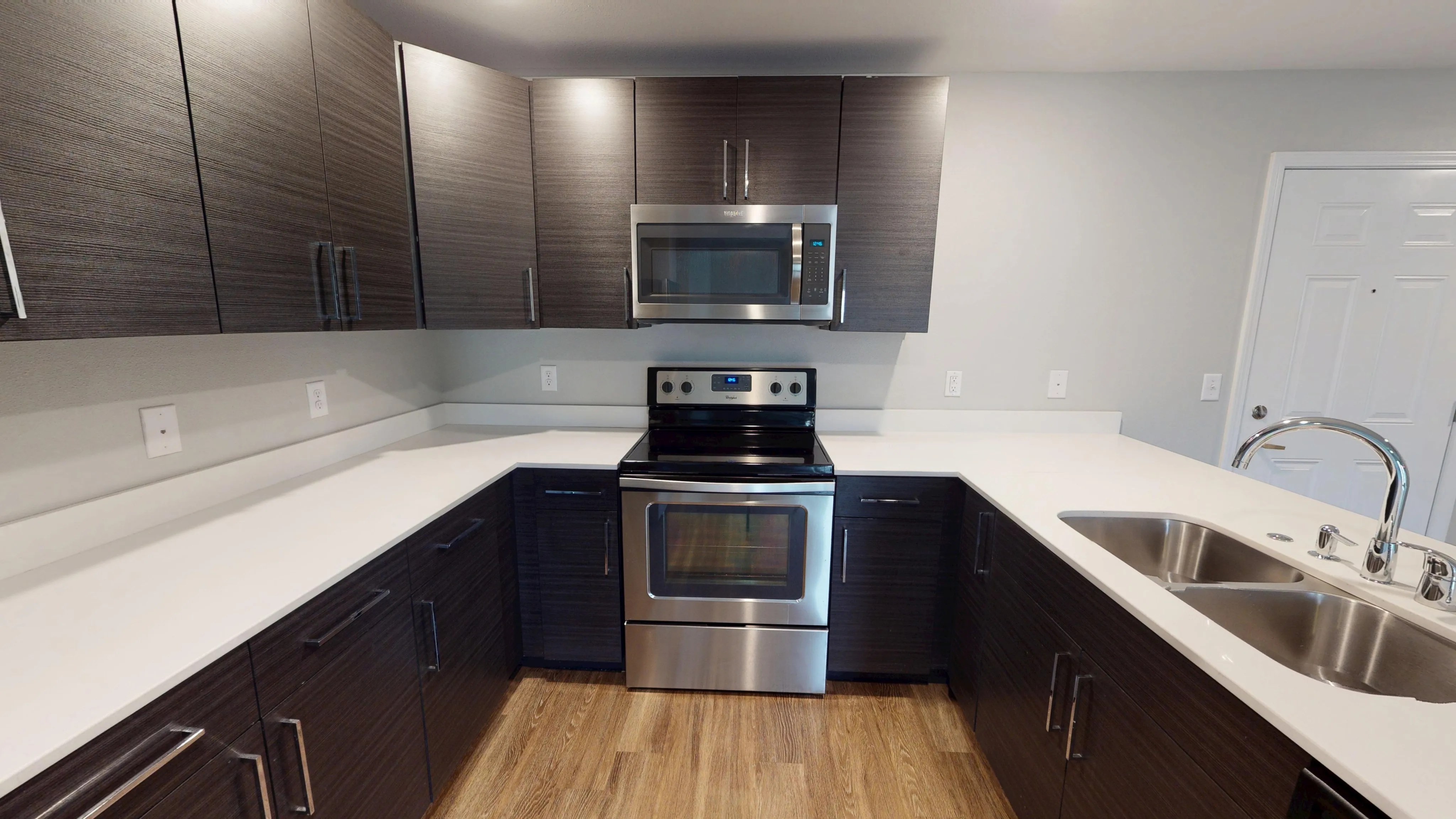 Modern kitchen with sleek dark cabinets, stainless steel appliances, and elegant countertops, creating a contemporary culinary space.