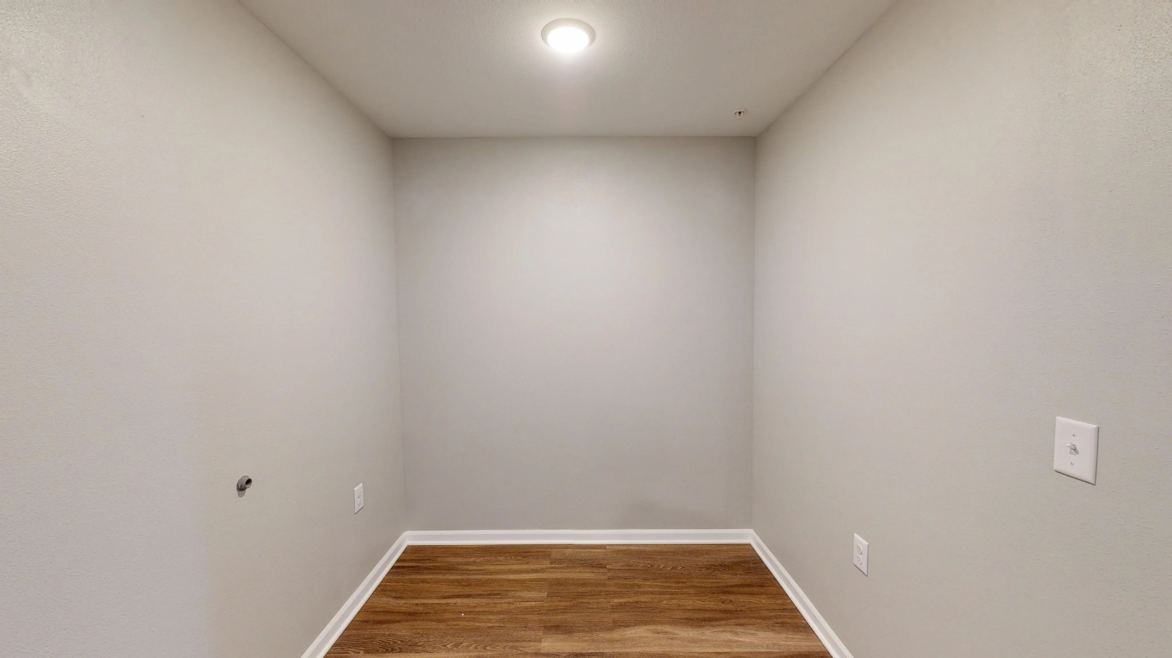 Cozy space with elegant gray walls and rich wooden flooring, perfect for a reading nook or office area.