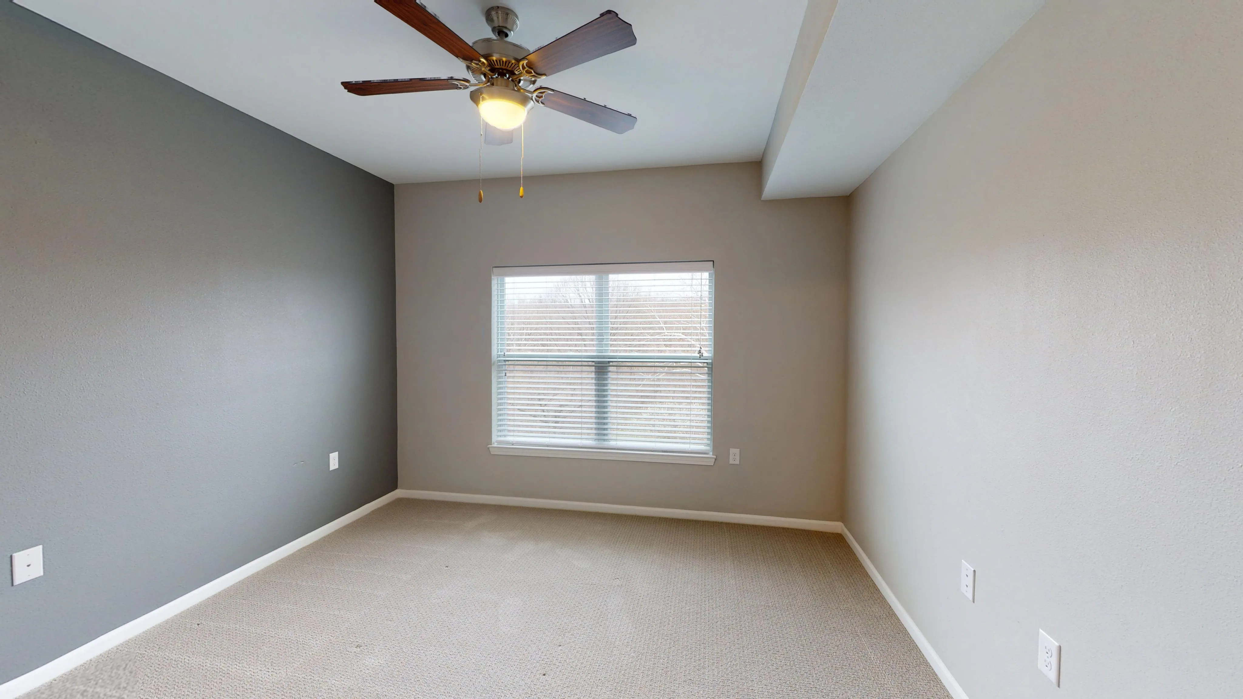Bright and airy bedroom with neutral walls, large window, and ceiling fan, perfect for relaxation.