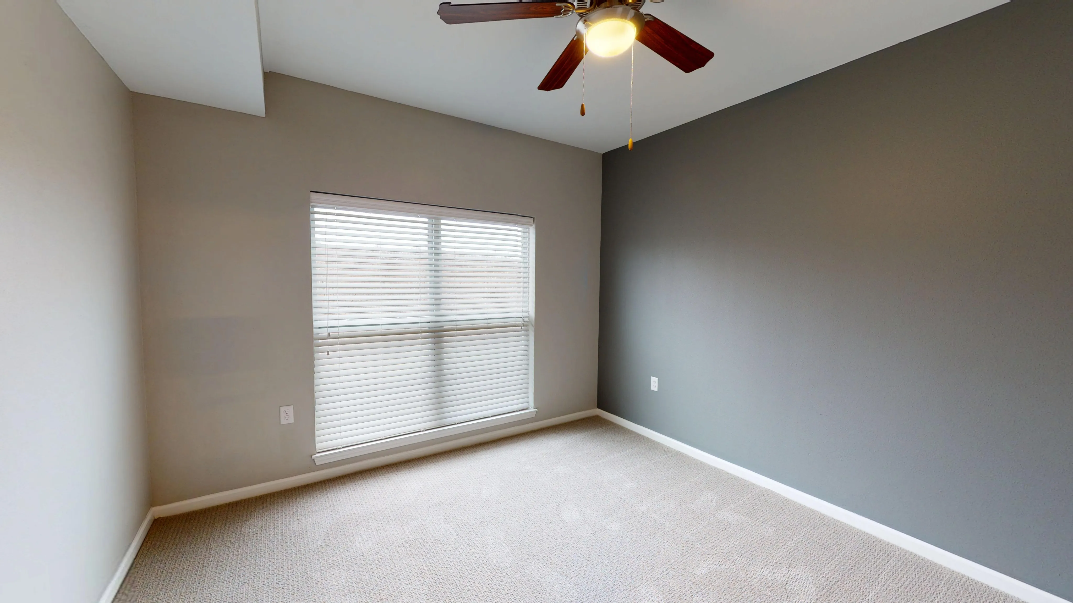 Bright and airy bedroom with neutral tones, modern ceiling fan, and large window with blinds.