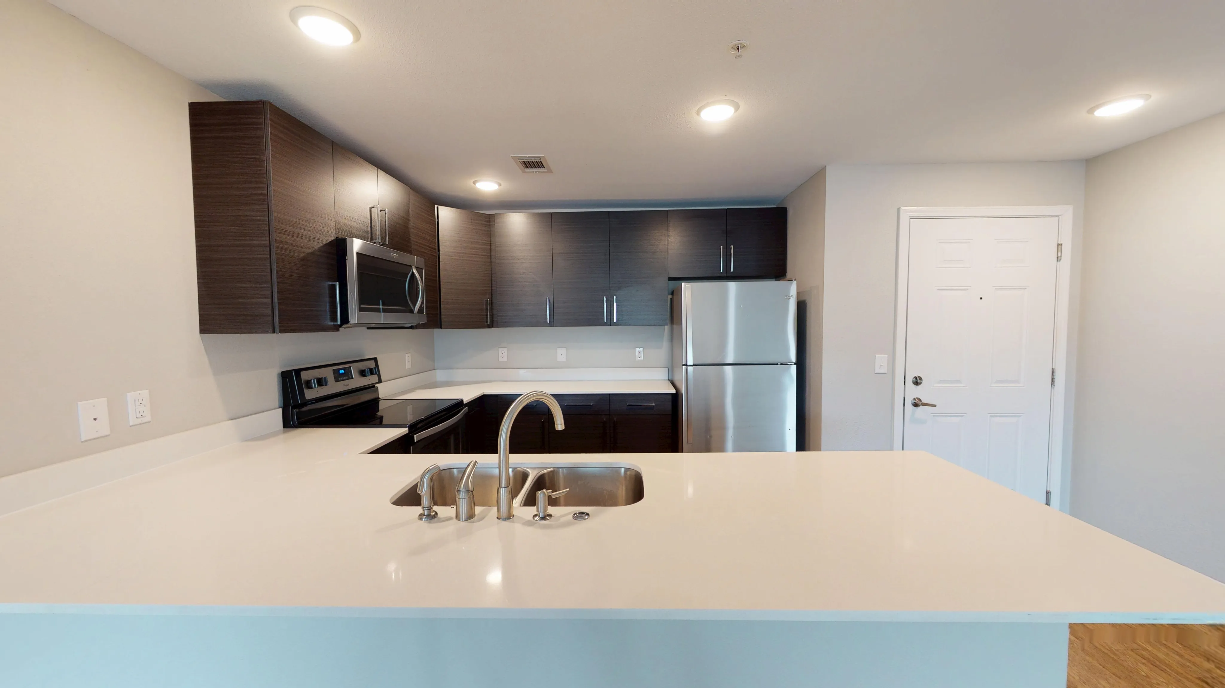 Modern kitchen with sleek dark cabinets, stainless steel appliances, and a spacious quartz countertop.