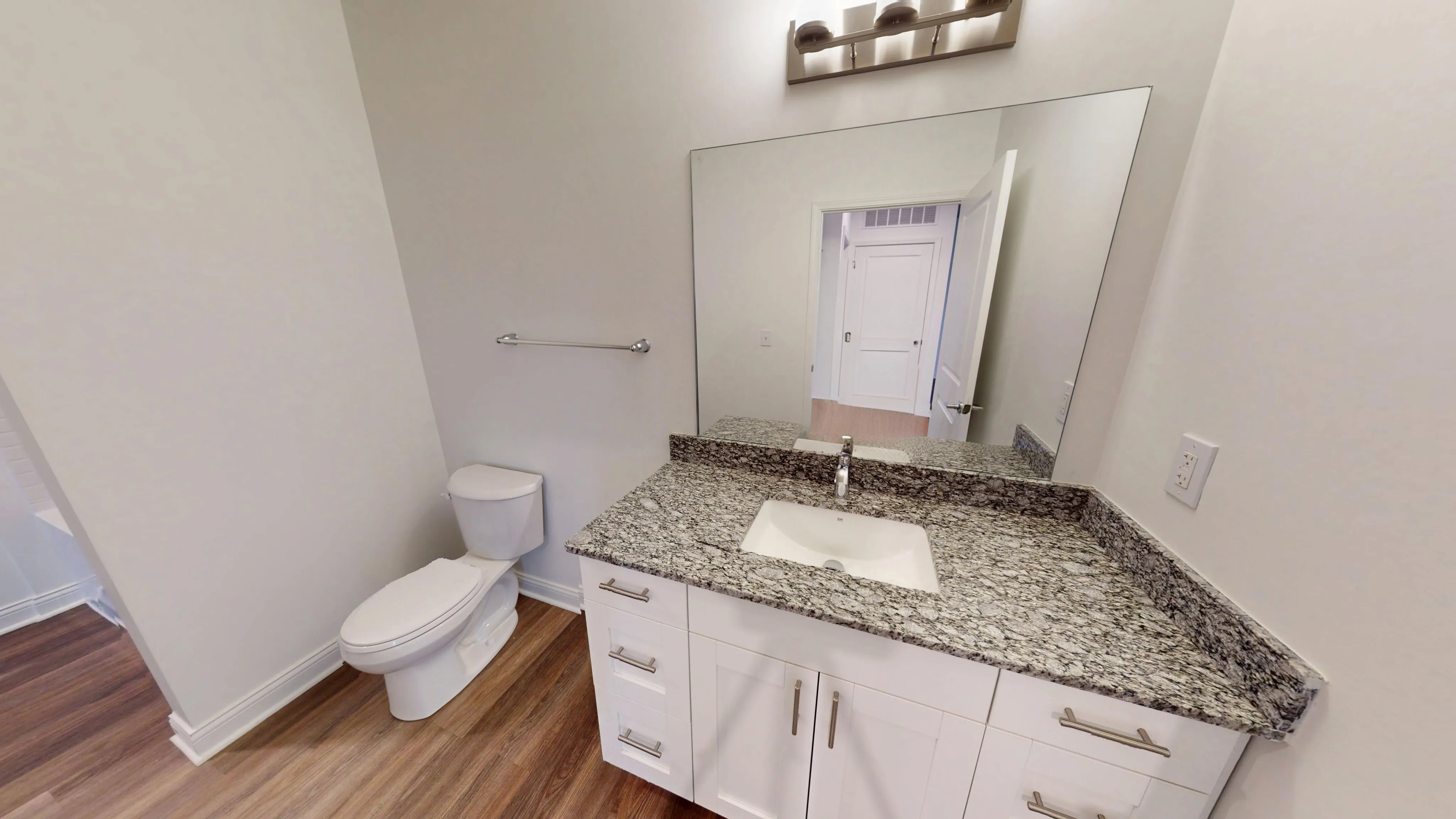 Modern bathroom with elegant granite countertop, sleek fixtures, and spacious mirror.
